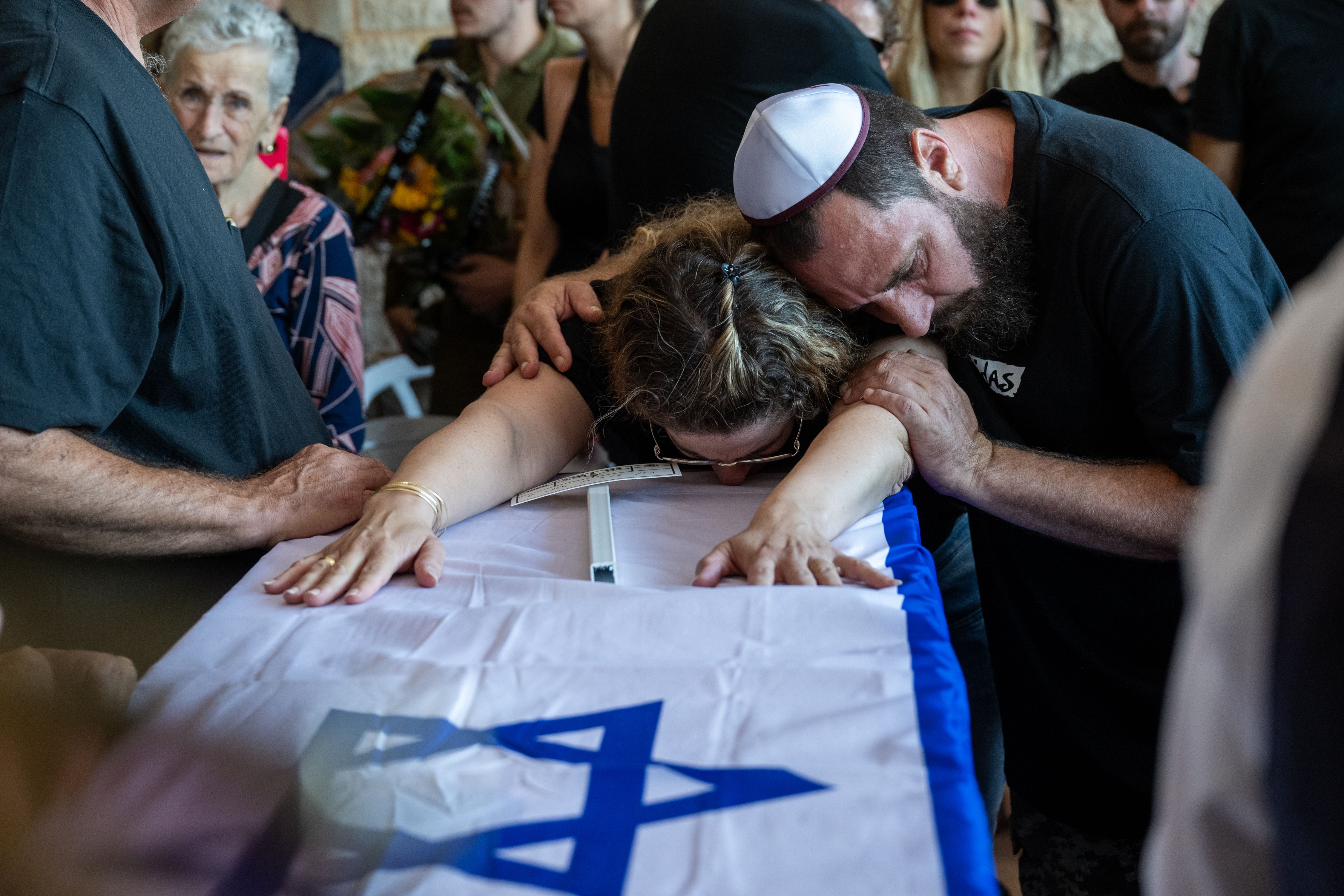 Family members grieve over a coffin covered in an Israeli flag during the funeral of four family members were killed in the Oct. 7 attack.