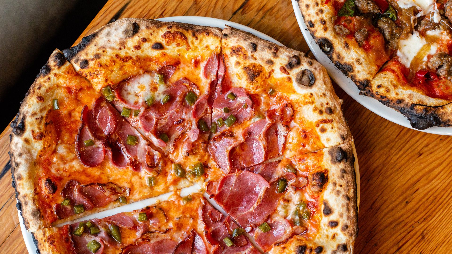 A photo of a pizza on a wood grain table.