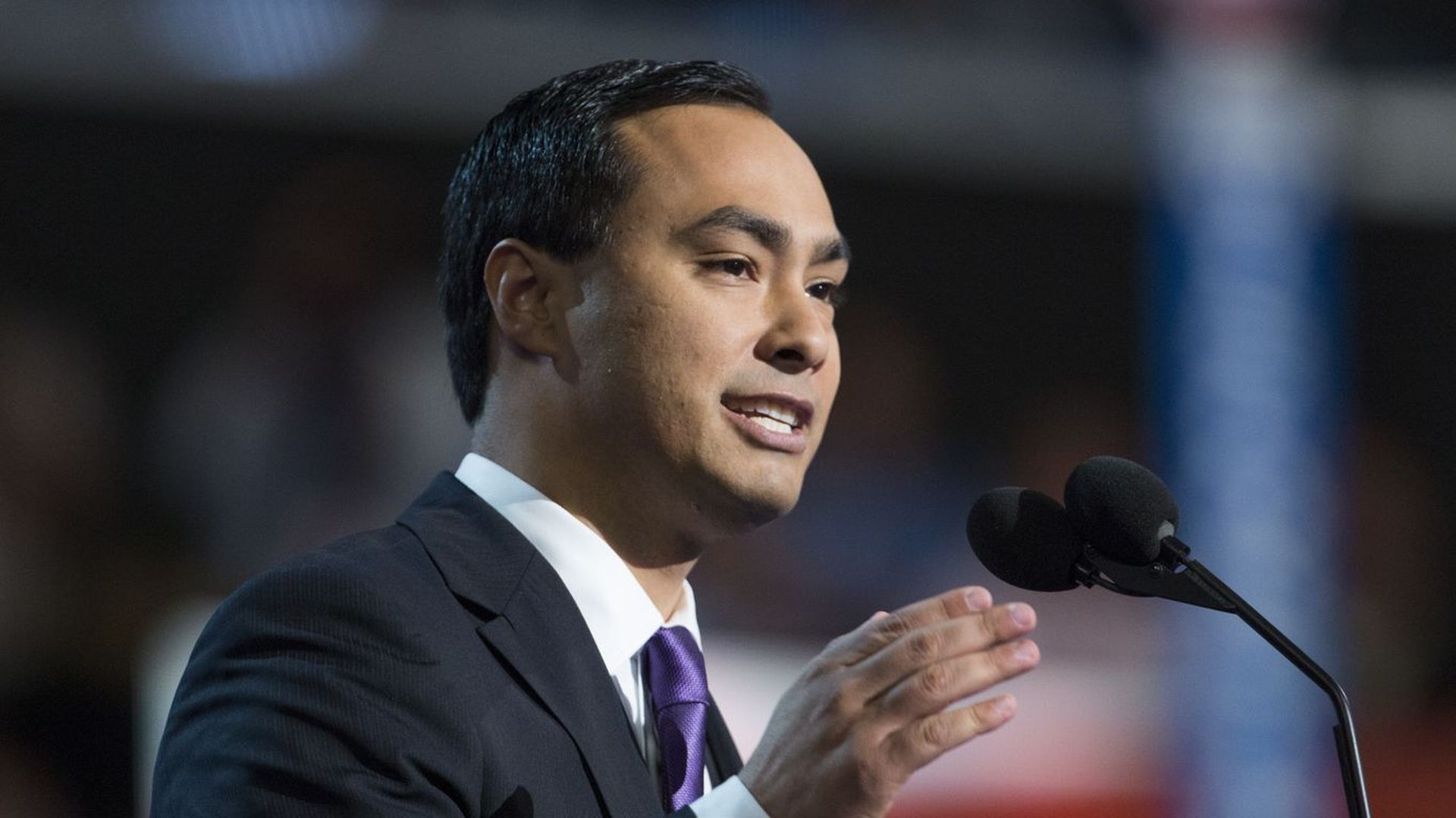 U.S. Rep. Joaquin Castro holds one hand up as he speaks in front of a microphone