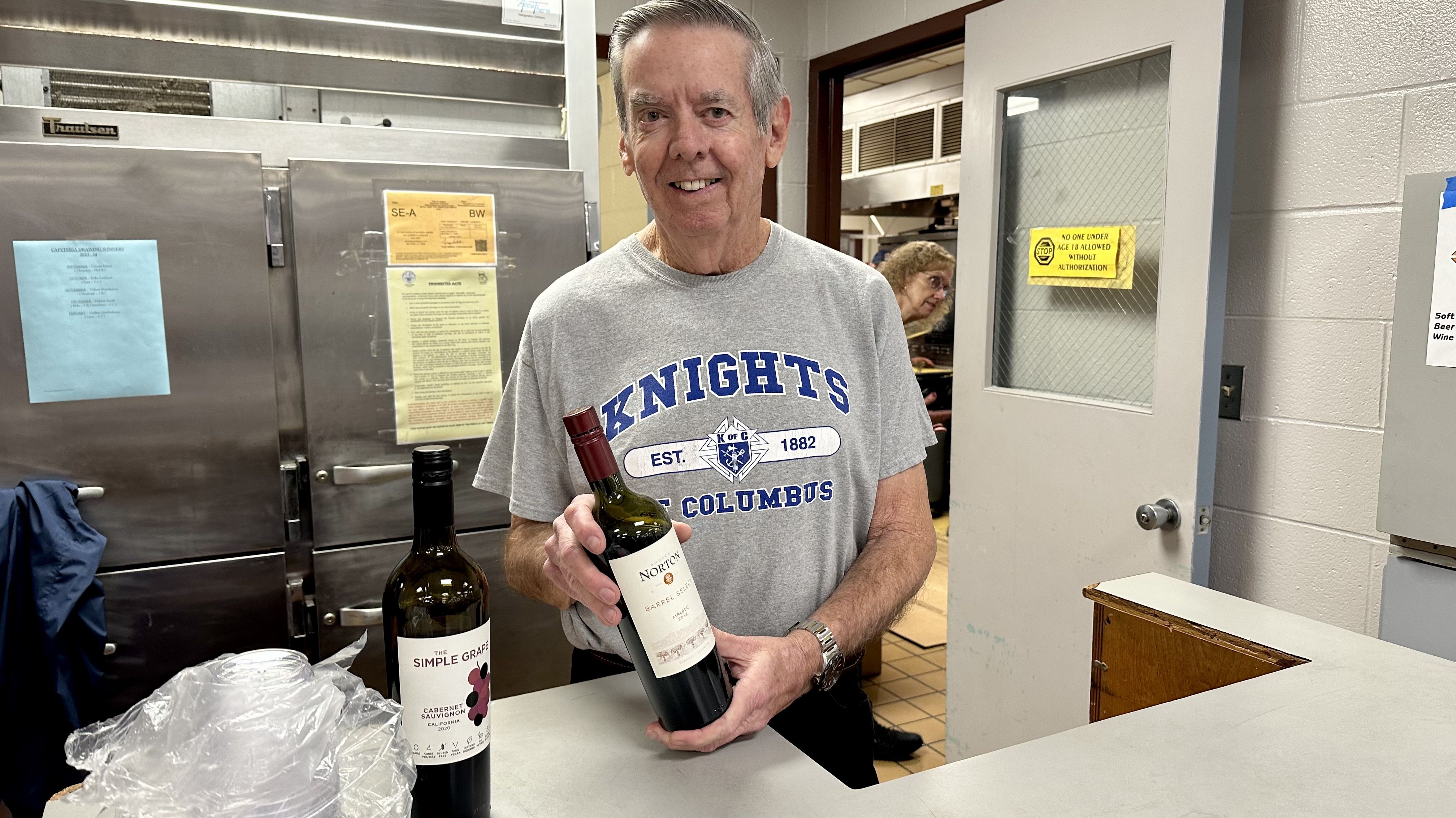 Photo shows a man holding a bottle of wine at the St. Ann fish fry in Metairie.