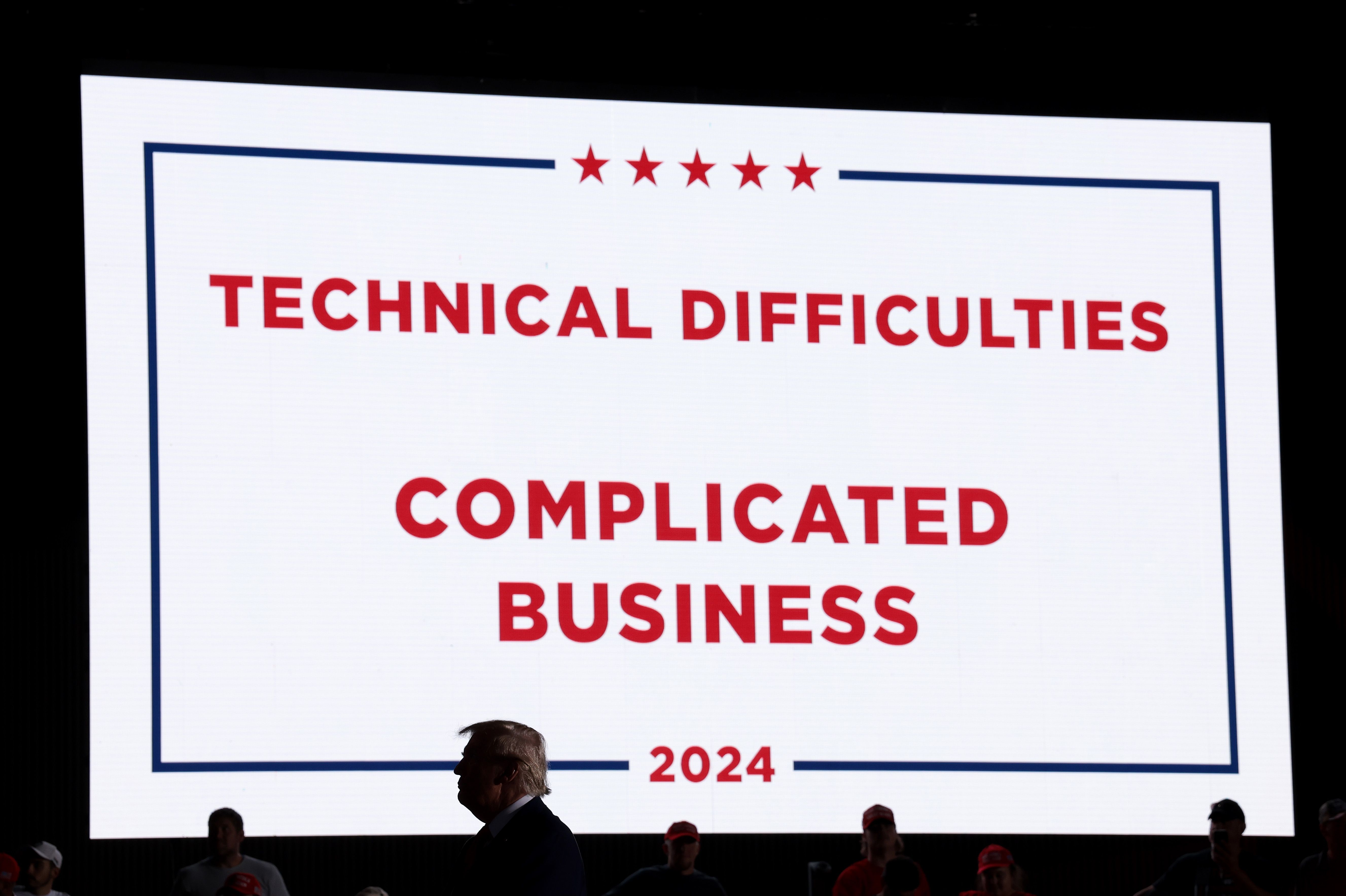 DETROIT, MICHIGAN - OCTOBER 18: Republican presidential nominee, former U.S. President Donald Trump, stands in front of a "technical difficulties" sign after his microphone stopped working during a campaign rally
