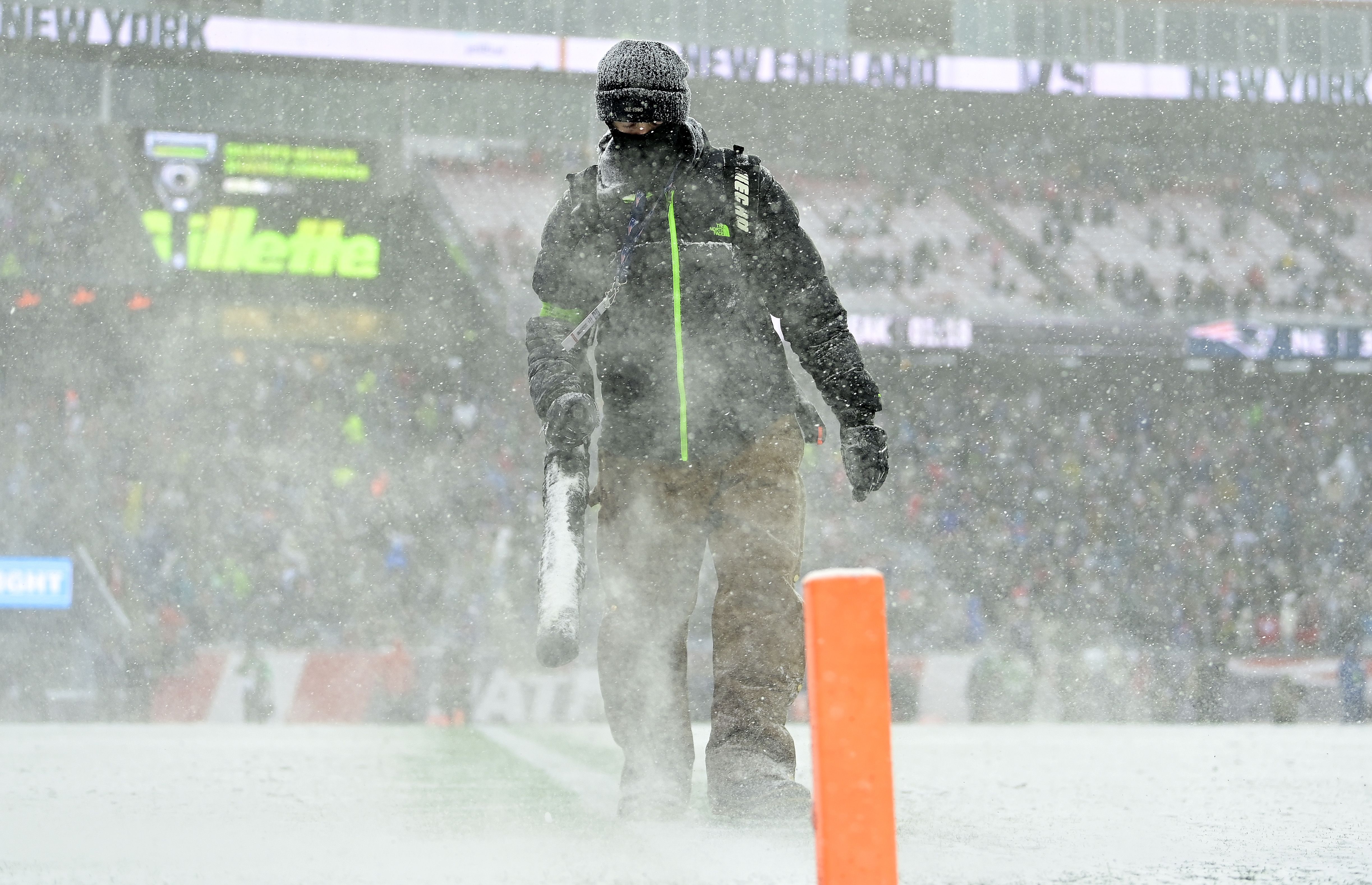 : Grounds crew members blow snow during the first half at Gillette Stadium on January 07, 2024 in Foxborough, Massachusetts. 