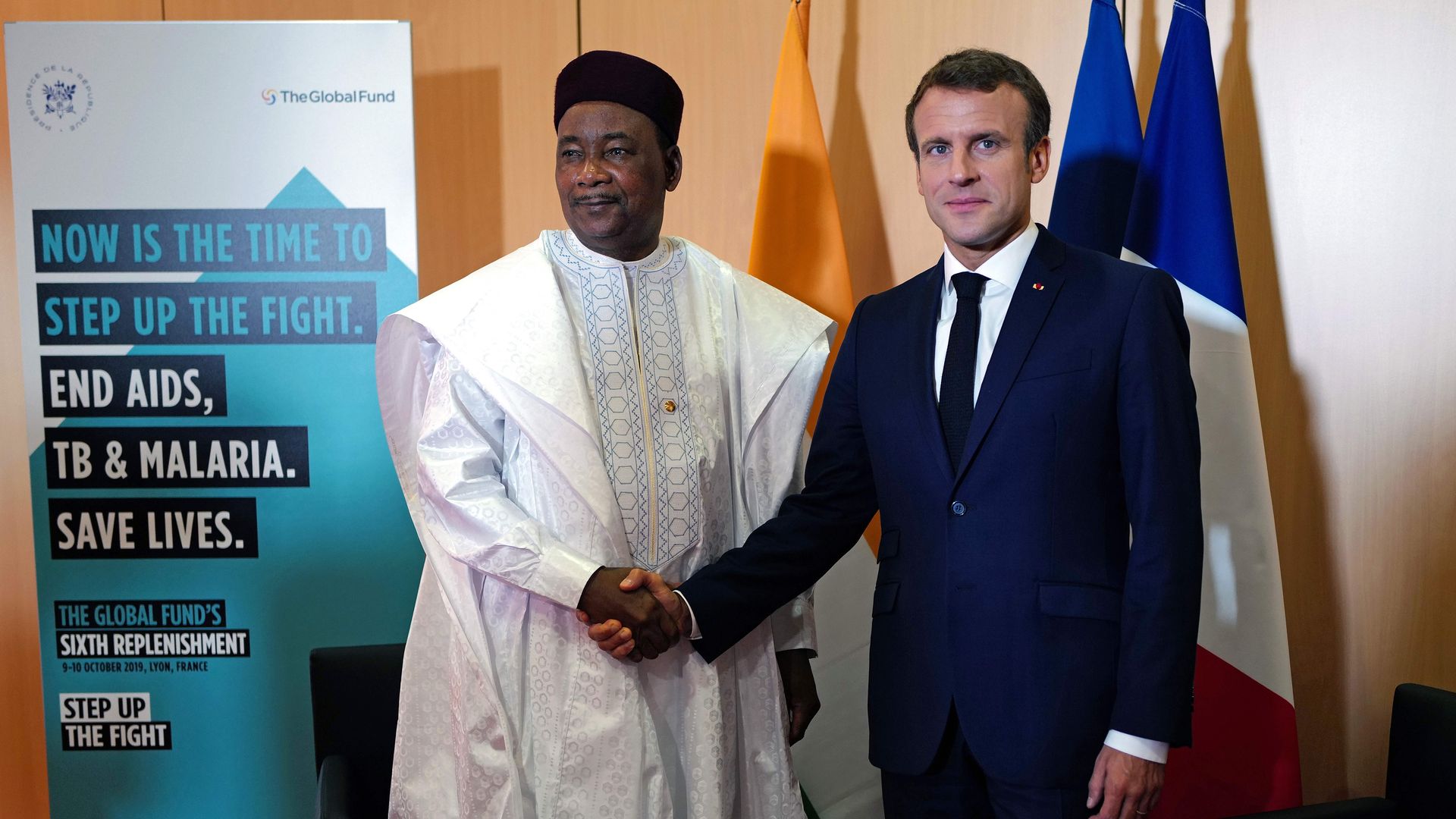 Emmanel Macron and Mahamadou Issoufou shake hands in front of flags and a Global Fund sign