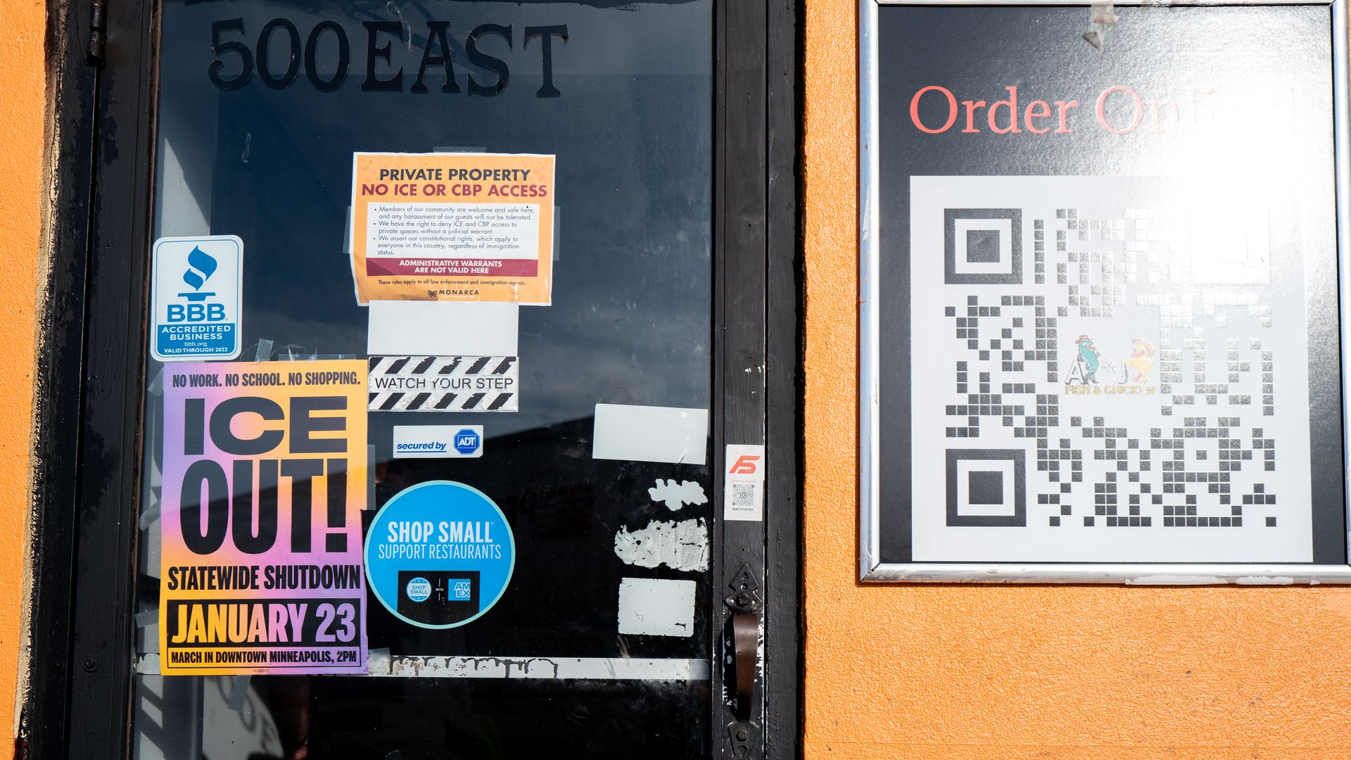 A glass business door with signs announcing it ICE OUT Statewide Shutdown on Jan. 23 and another telling ICE to stay out. 