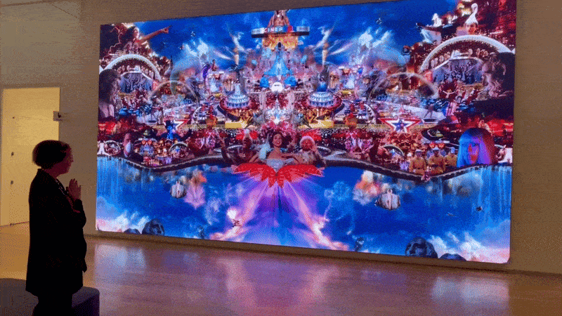 A moving image shows a person gesturing toward a colorful video illustration.