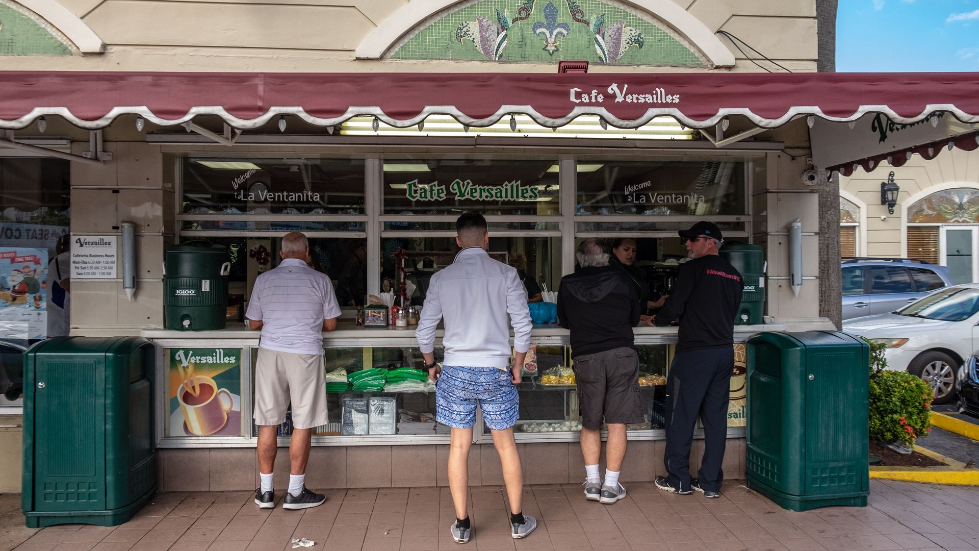 Four men stand outside the Versailles ventanita. 
