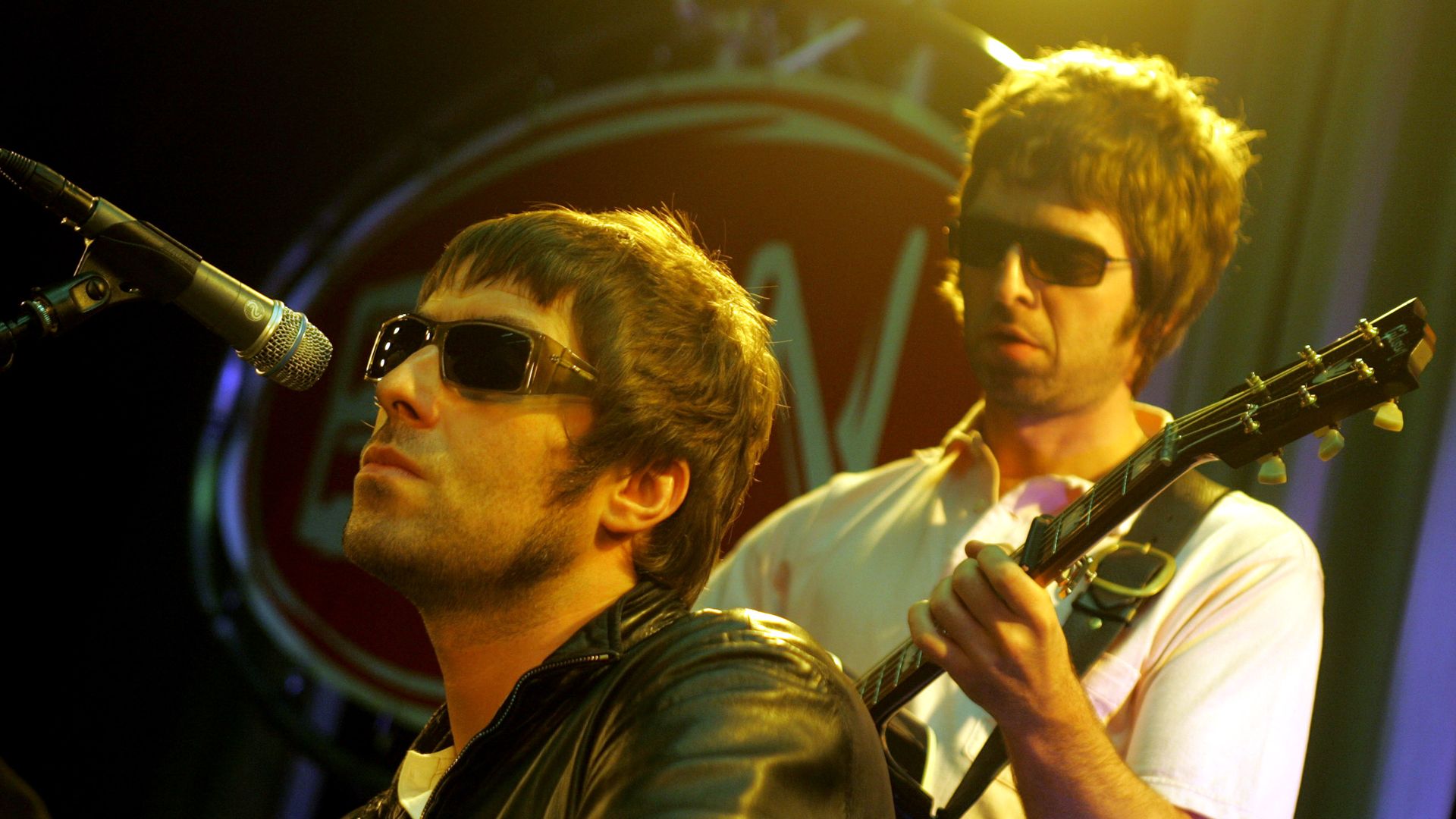 Liam and Noel Gallagher of Oasis perform on stage.