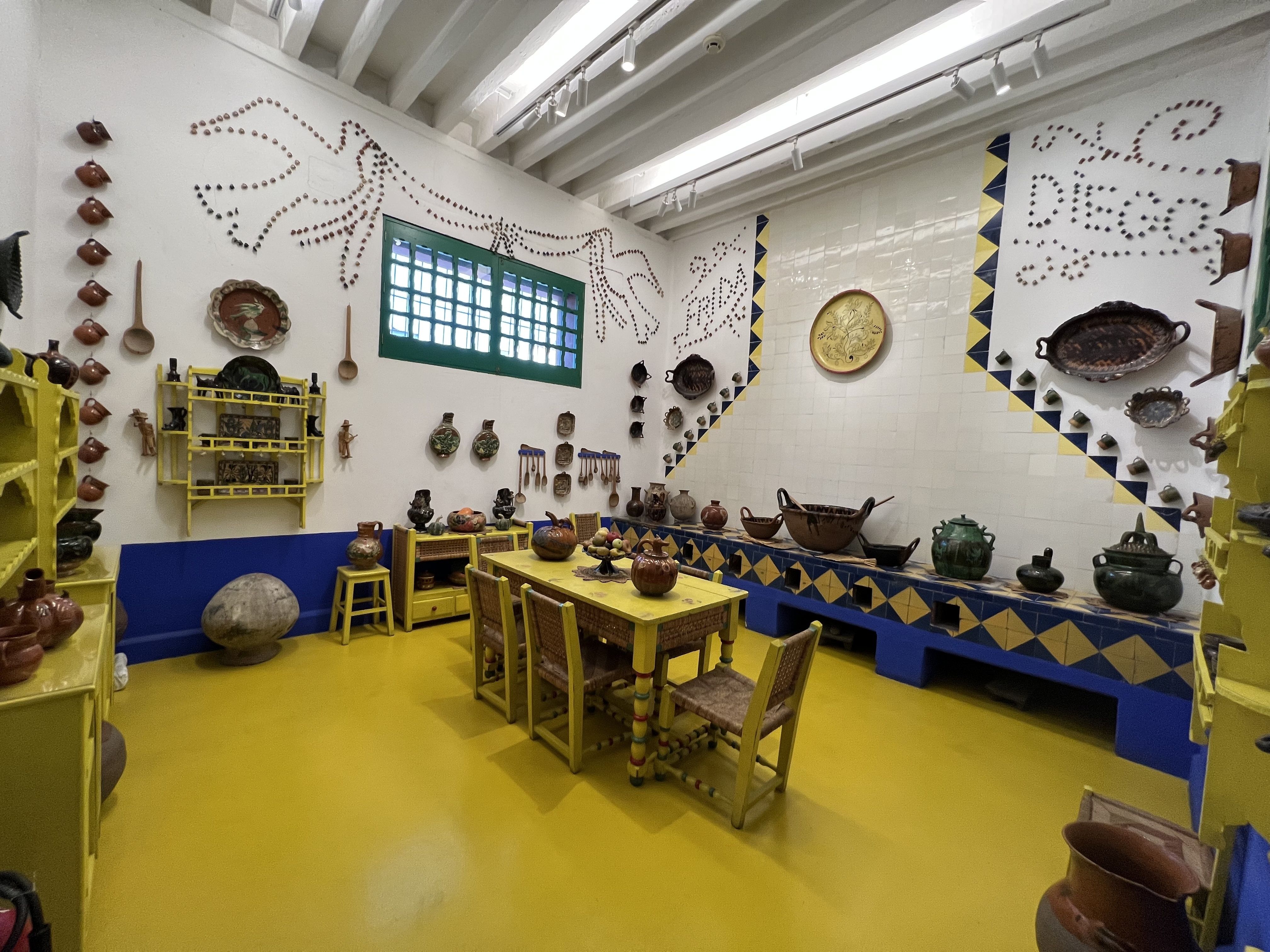 Bright yellow floors and different adobe pots decorate the kitchen in Casa Azul
