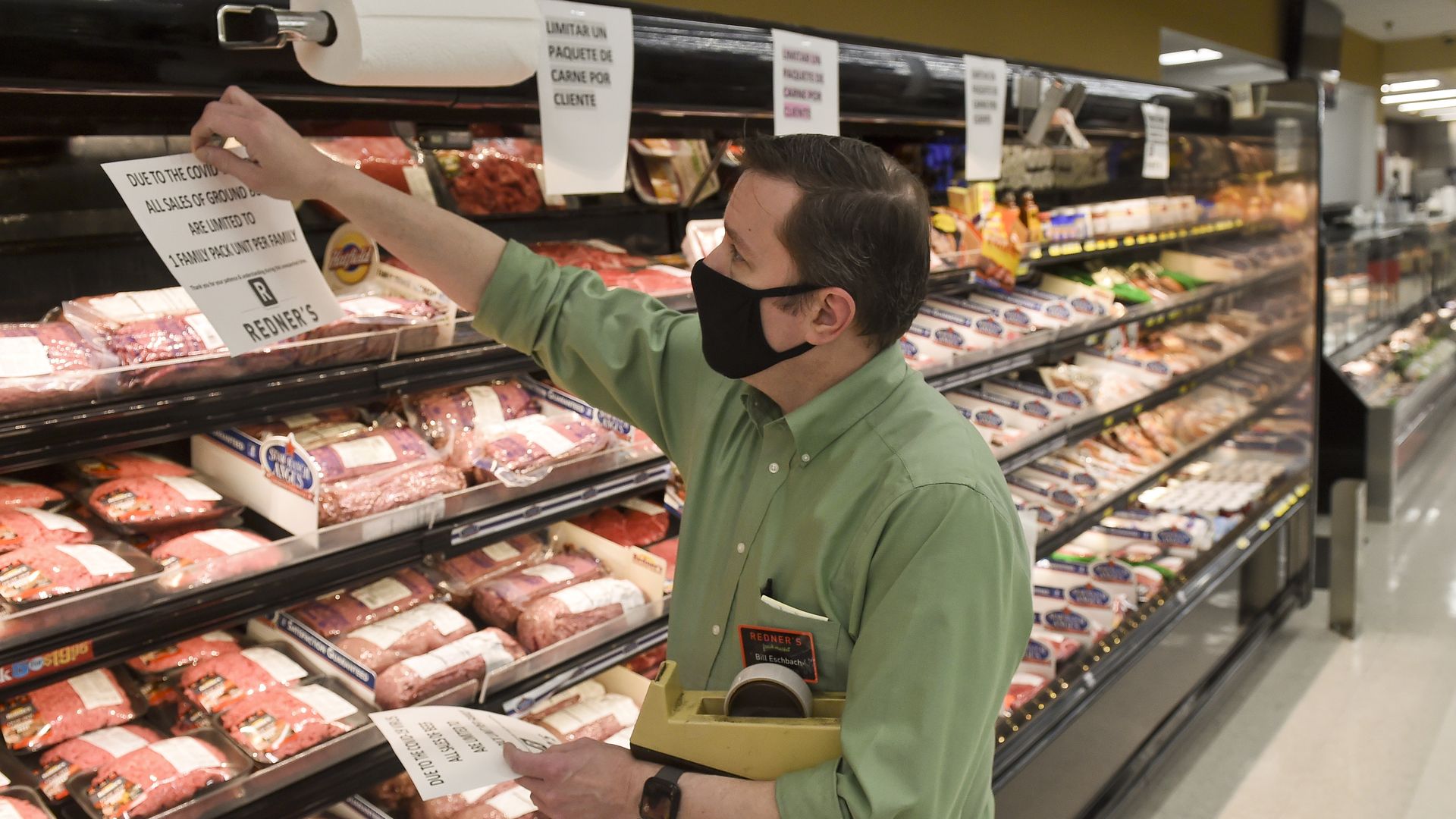 Store Director Bill Eschbach hangs up a sign in the beef section that reads "Due to the COVID-19 virus all sales of beef are limited to 1 family pack unit per family."