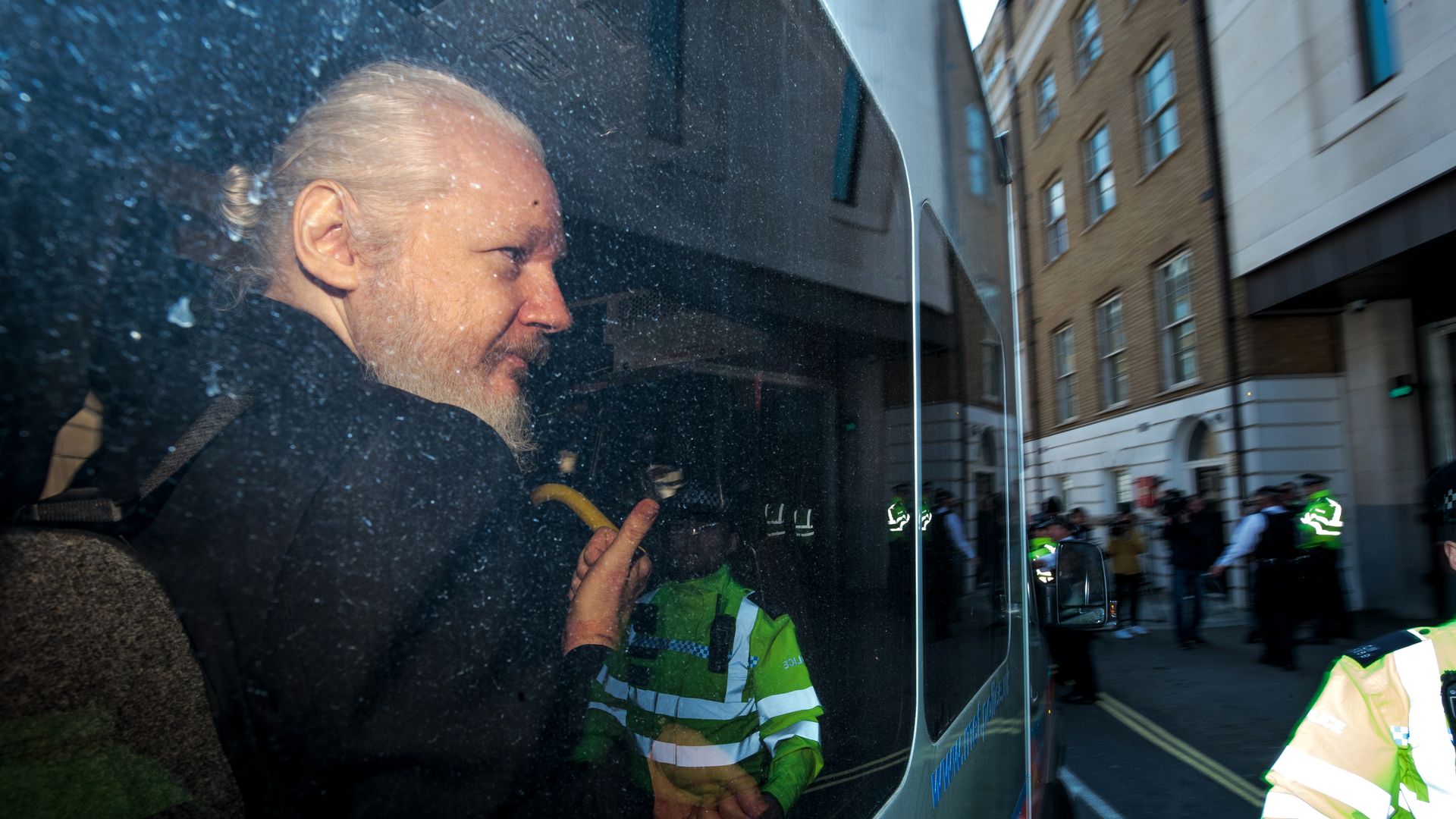 In this image, Julian Assange looks out a vehicle window. 