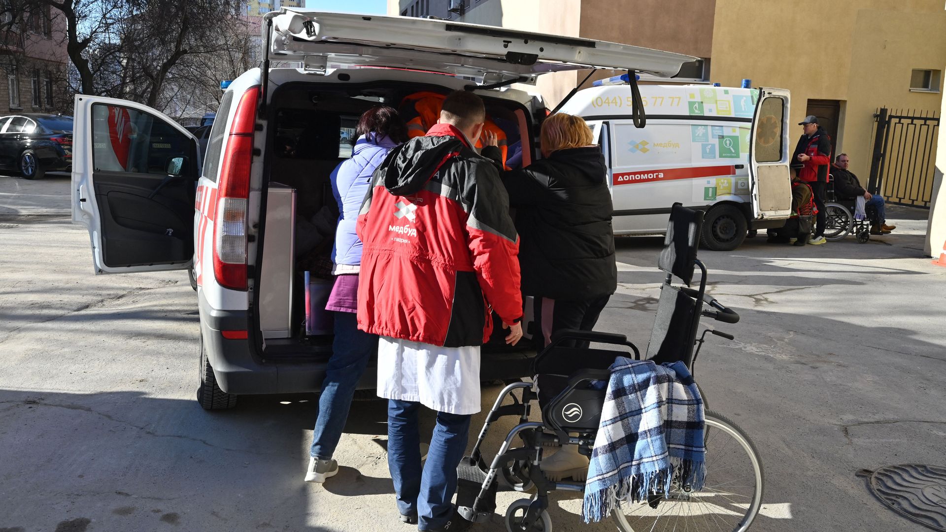 Medical personnel evacuate patients from a hospital not far from a high-rise apartment block which was hit by recent shelling in Kyiv.