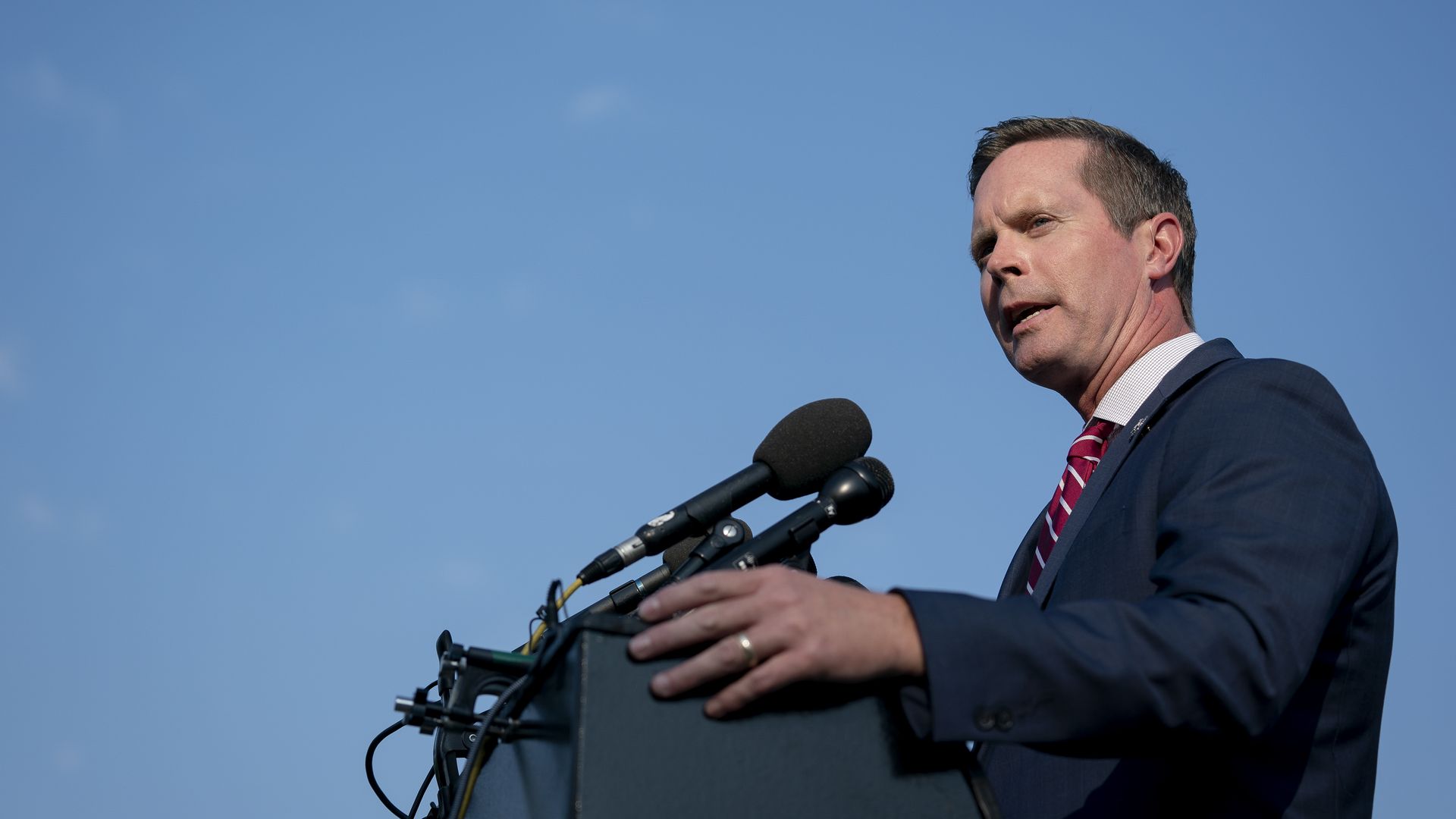 A man speaks in front of a podium.