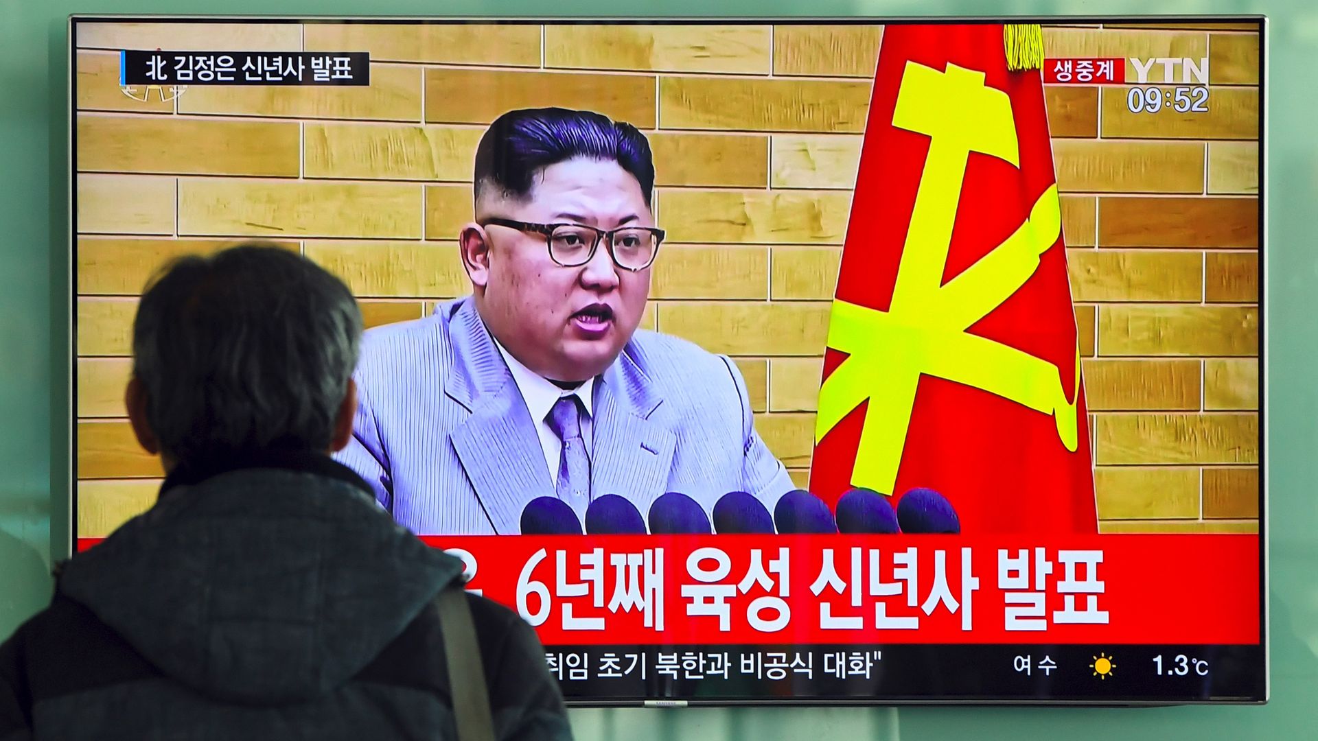 A man watches a television news broadcast showing Kim Jong-Un.