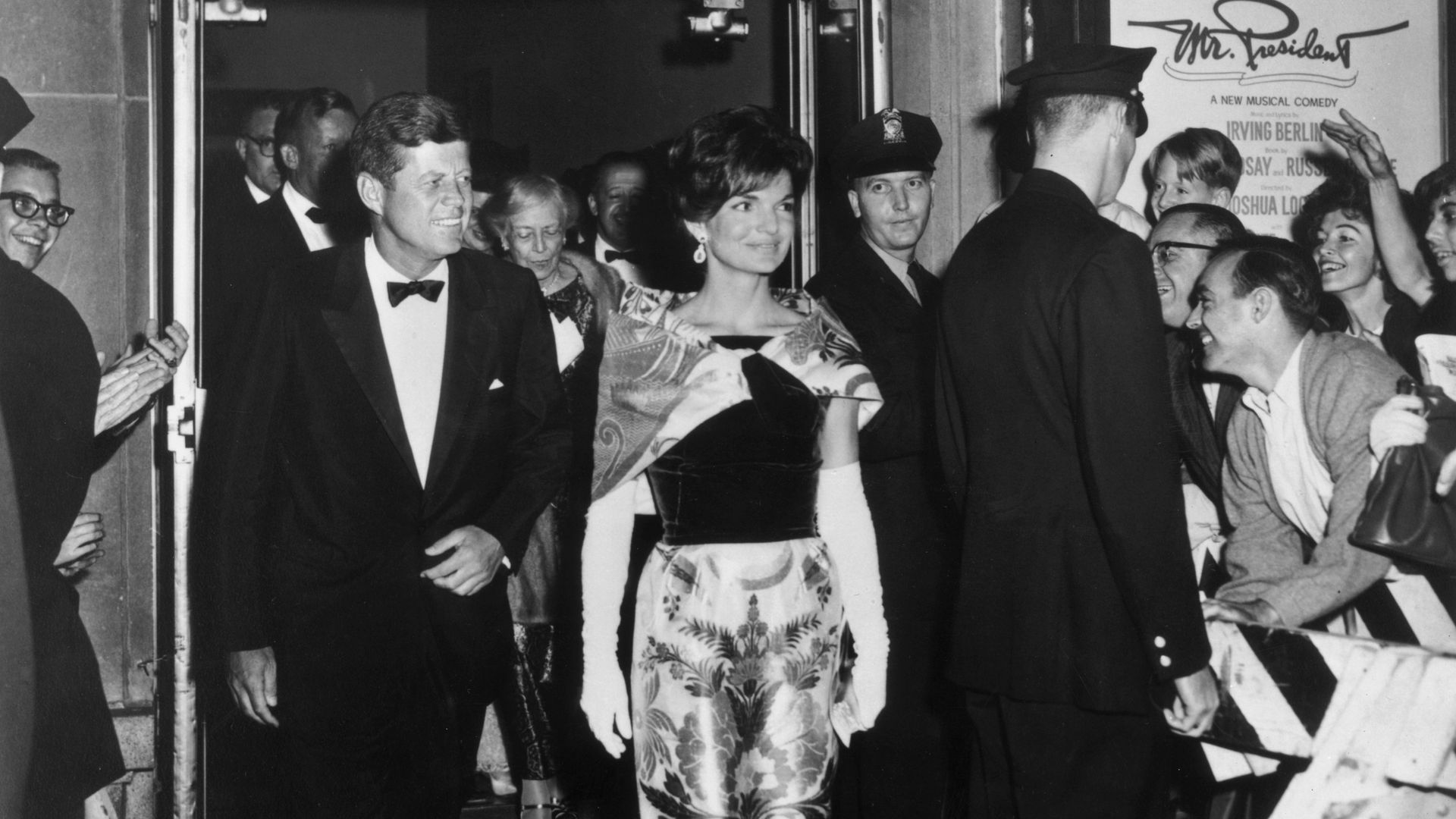 A black-and-white photo of John F. Kennedy, Jr. and Jackie Kennedy walking out of a theater.