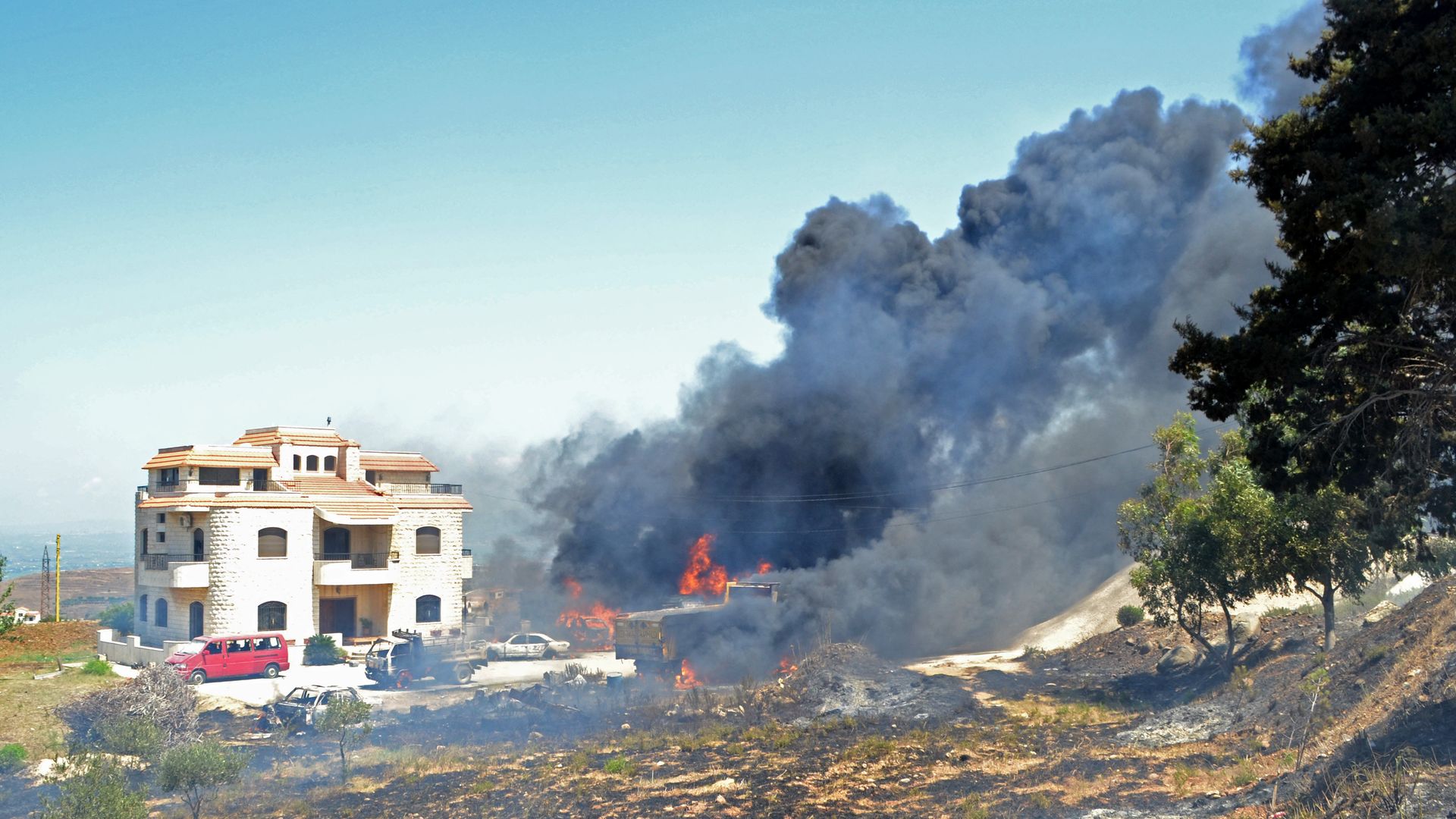 Vehicles burn outside the reported home of the lot owner, where the exploded fuel tank was placed, in the village of Tlel in Lebanon's northern region of Akkar on August 15