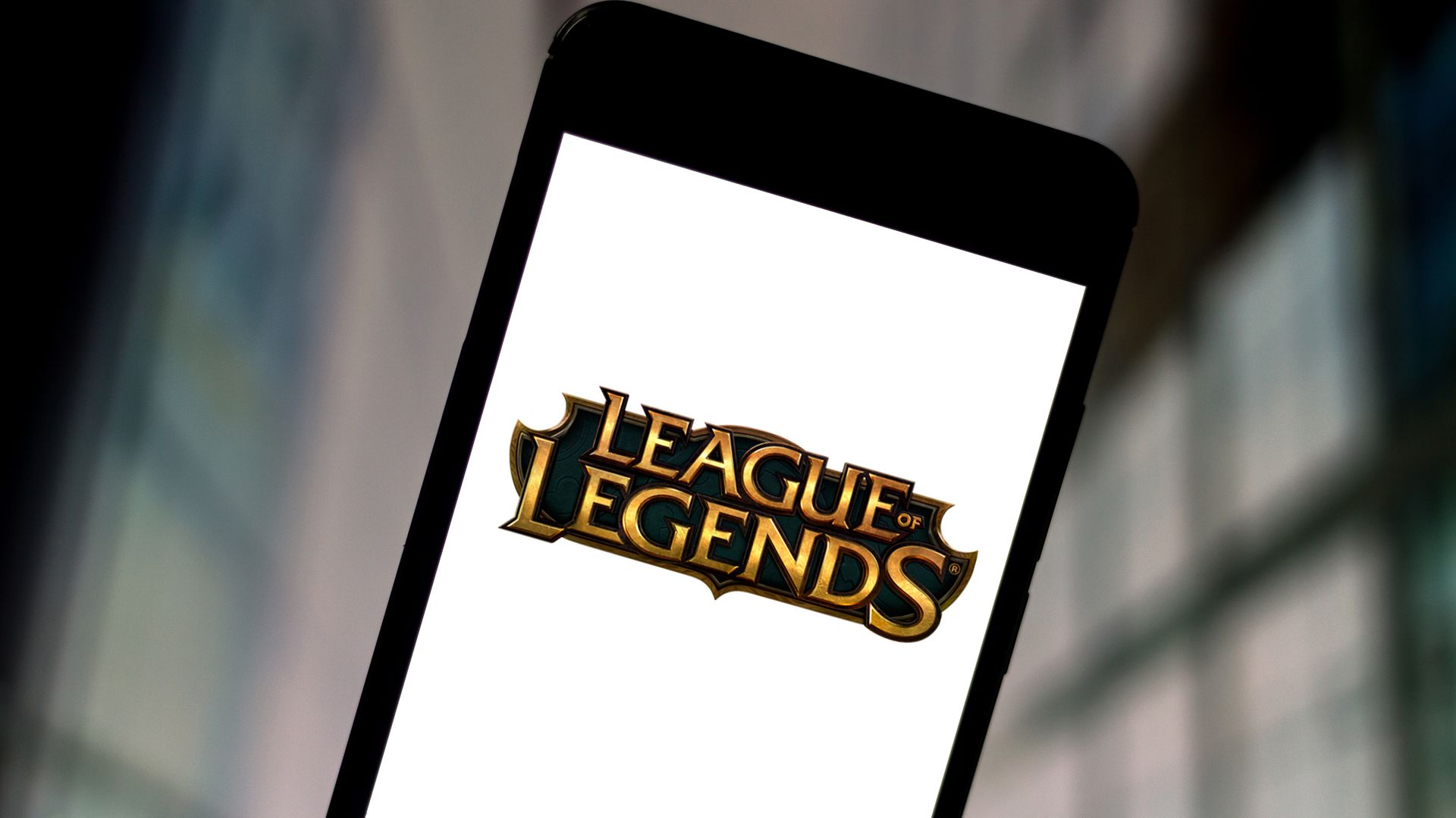 A  photo illustration a League of Legends logo seen displayed on a smartphone.