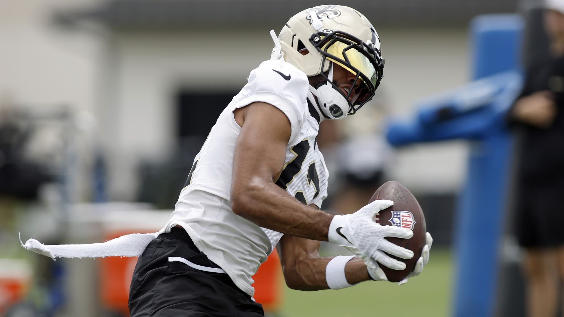 Chris Olave makes a catch in a practice uniform, wearing a gold Saints helmet and gold sun shades.