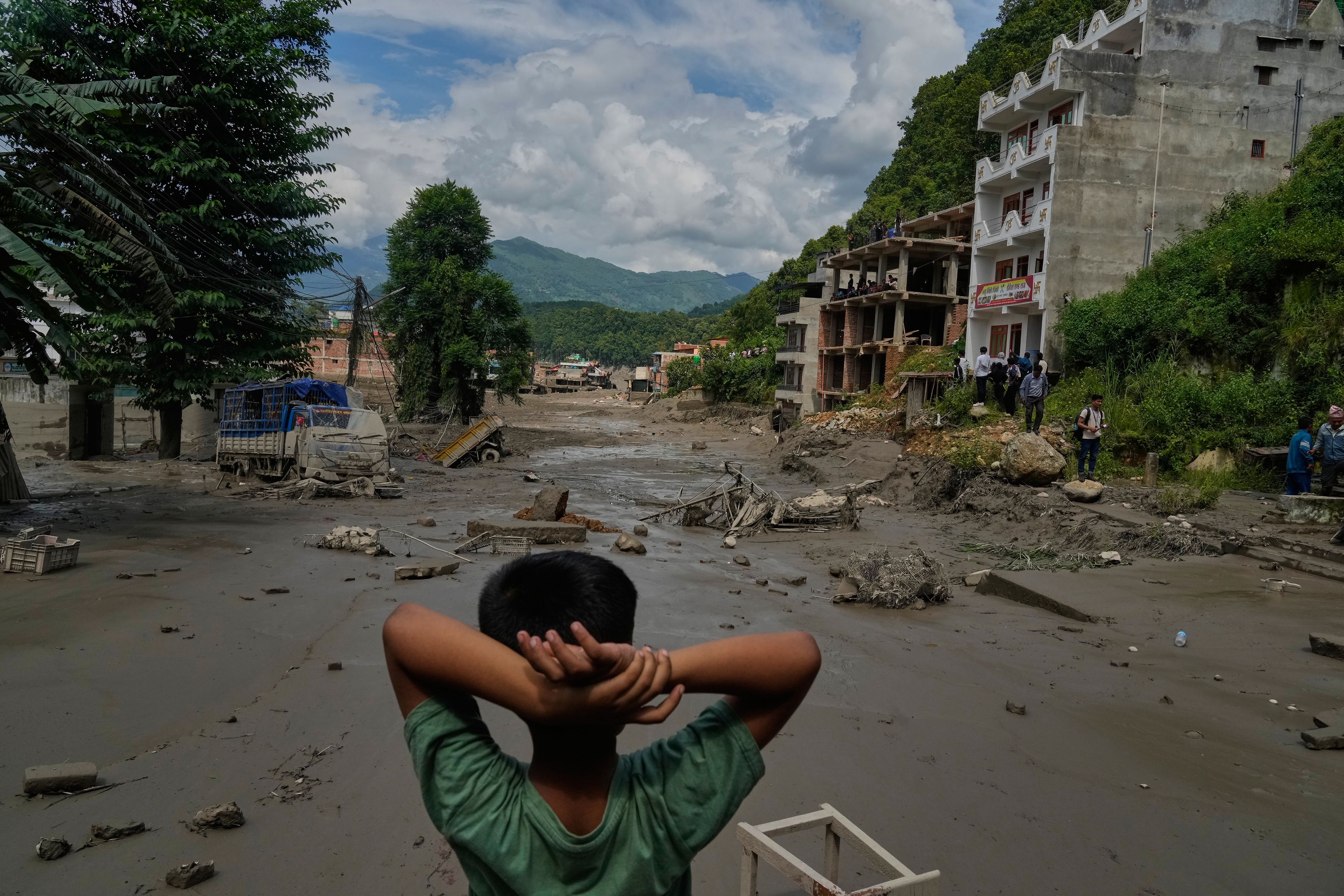 A boy looks at the devastation caused by flash flooding along the Trishuli River in Nepal today. AP Photo/Niranjan Shrestha