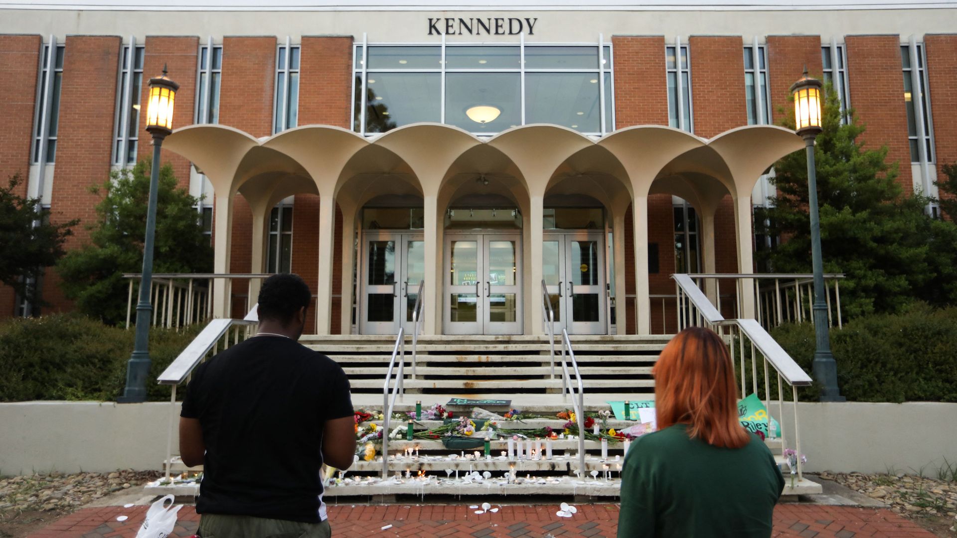 Students lay candles and flowers at the steps of Kennedy Hall