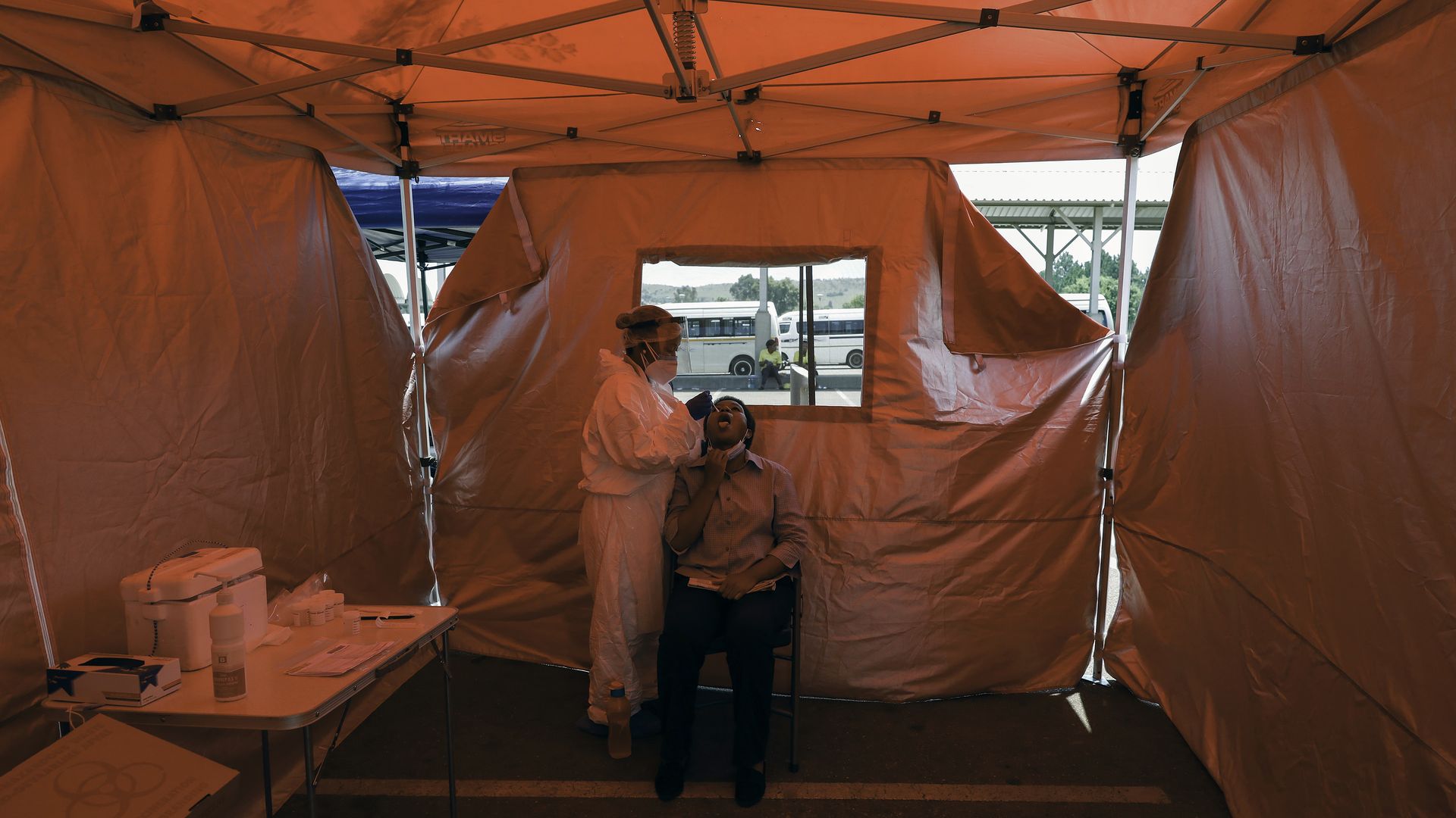 A person in PPE administers a COVID swab test