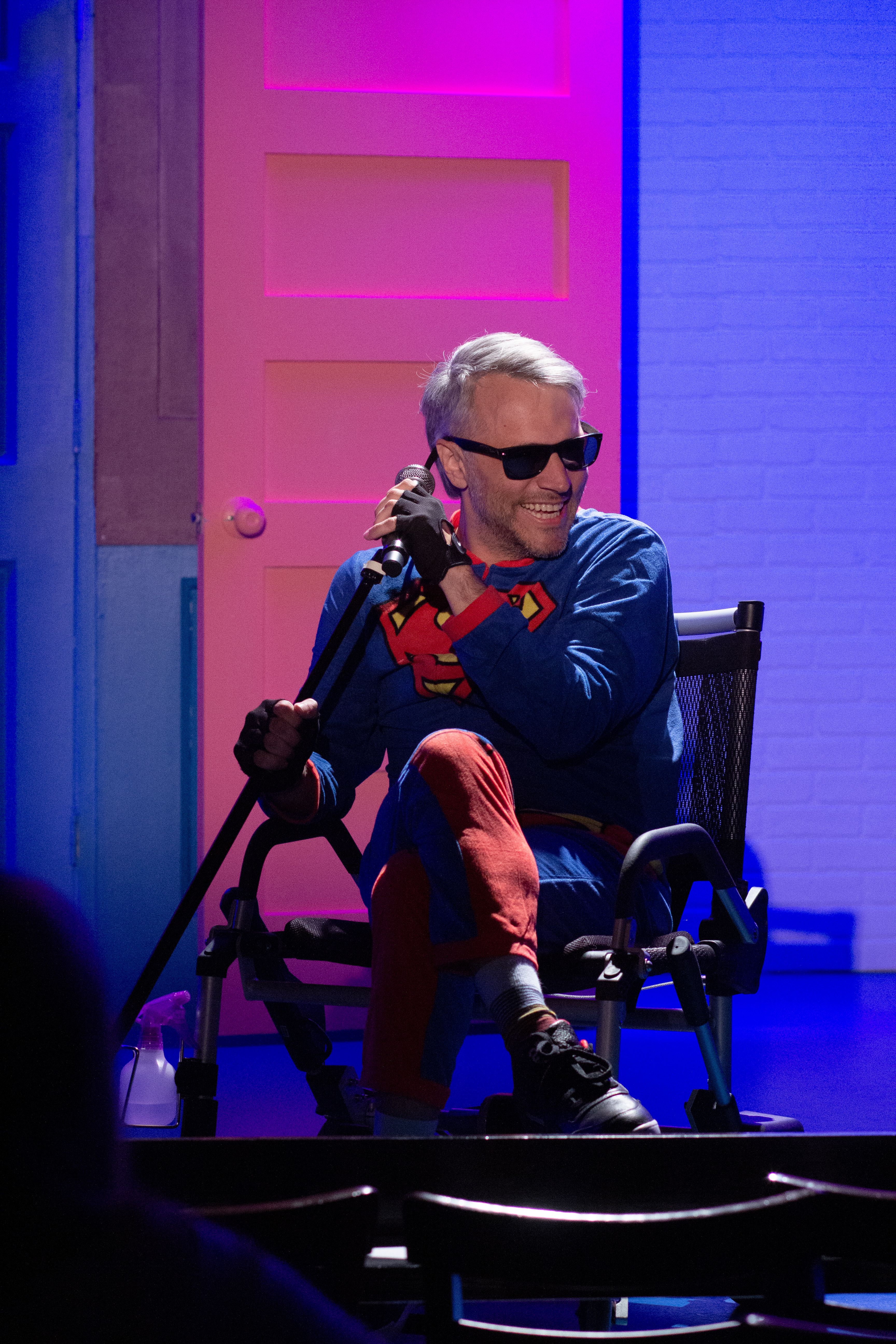 Photo of a man in a wheelchair performing live on stage. 