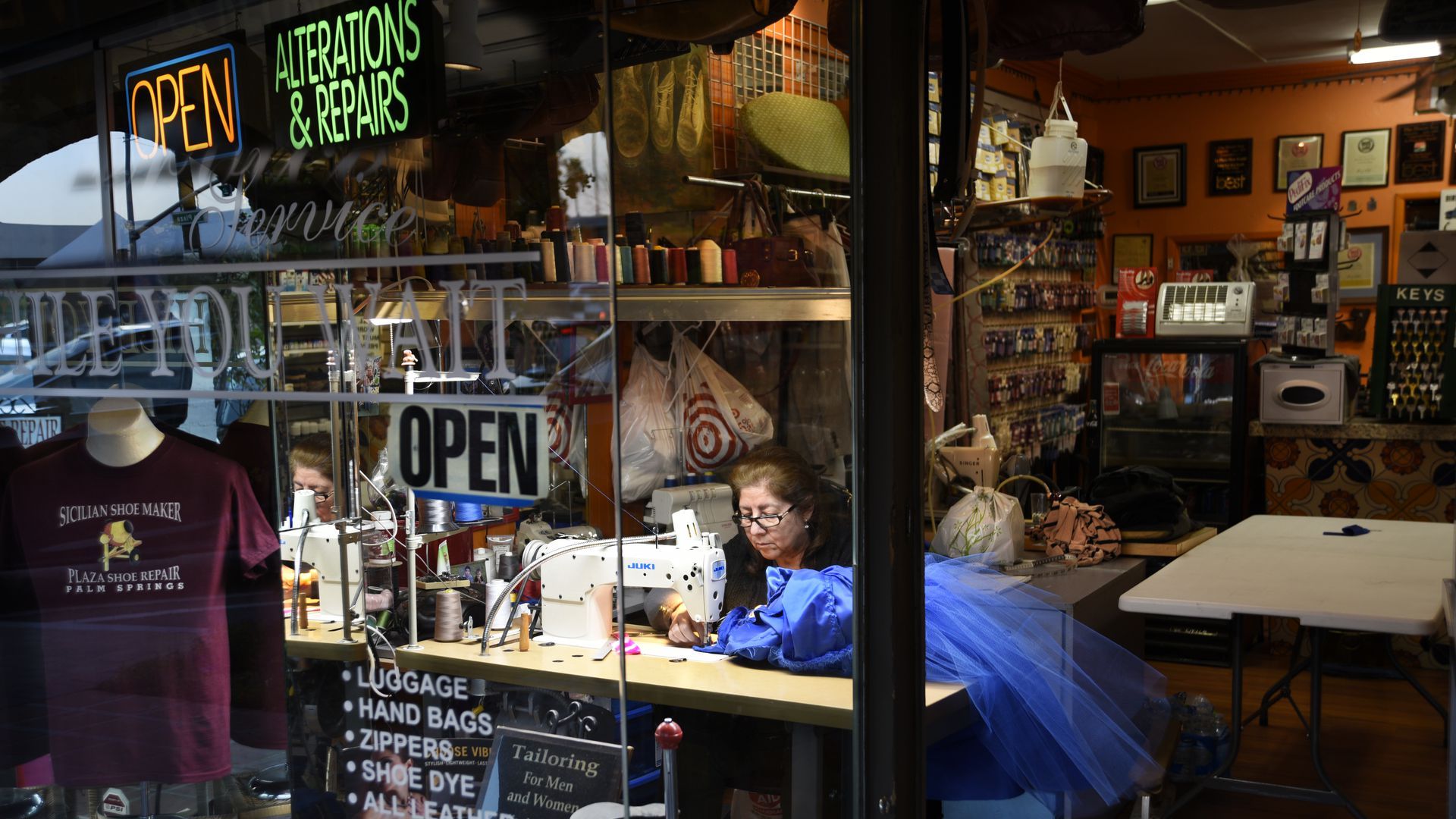 A seamstress works at a sewing machine in a tailoring shop.