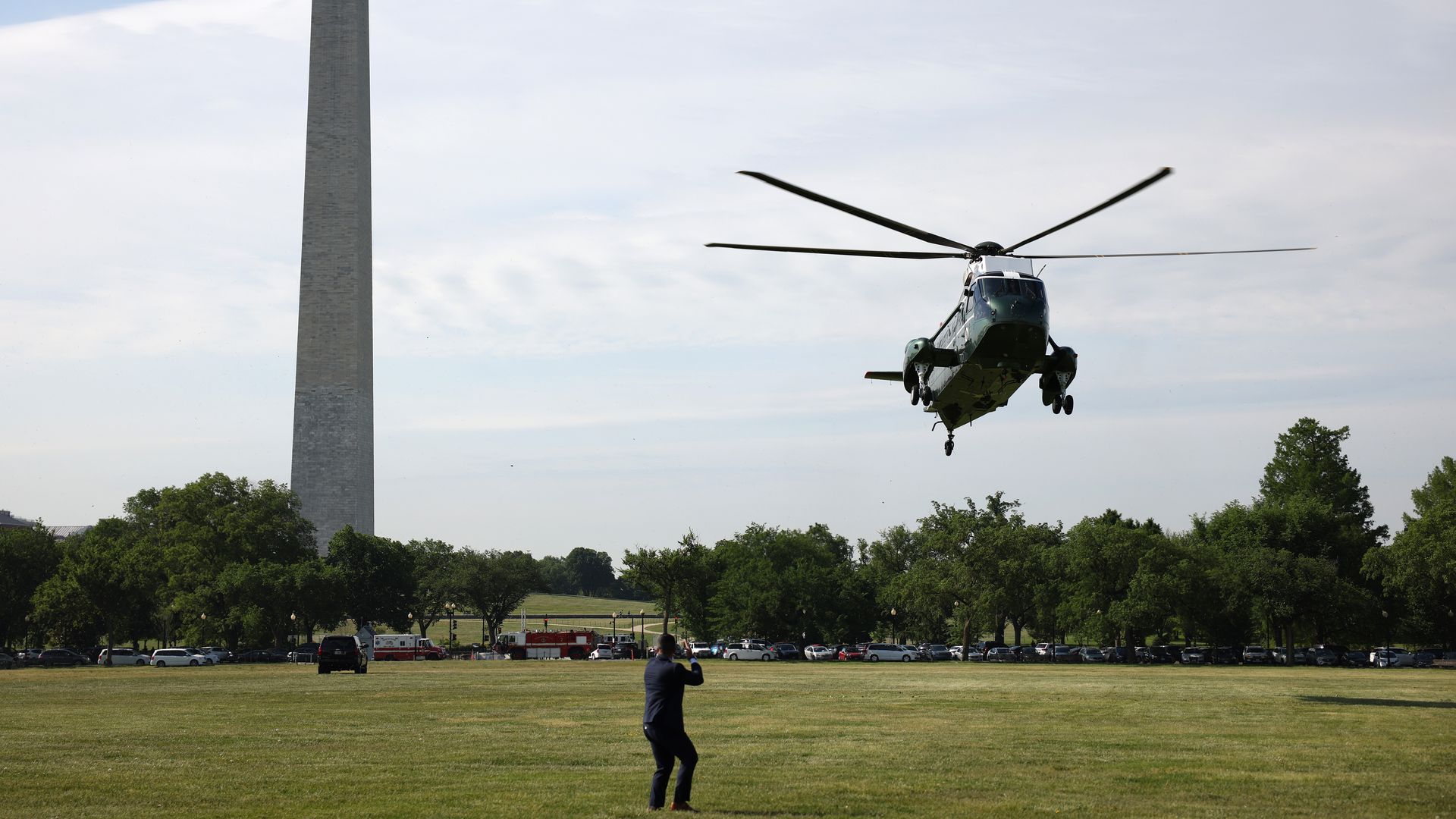 A ground crew member is seen bracing against the rotor-wash of Marine One as it lands on the Ellipse.