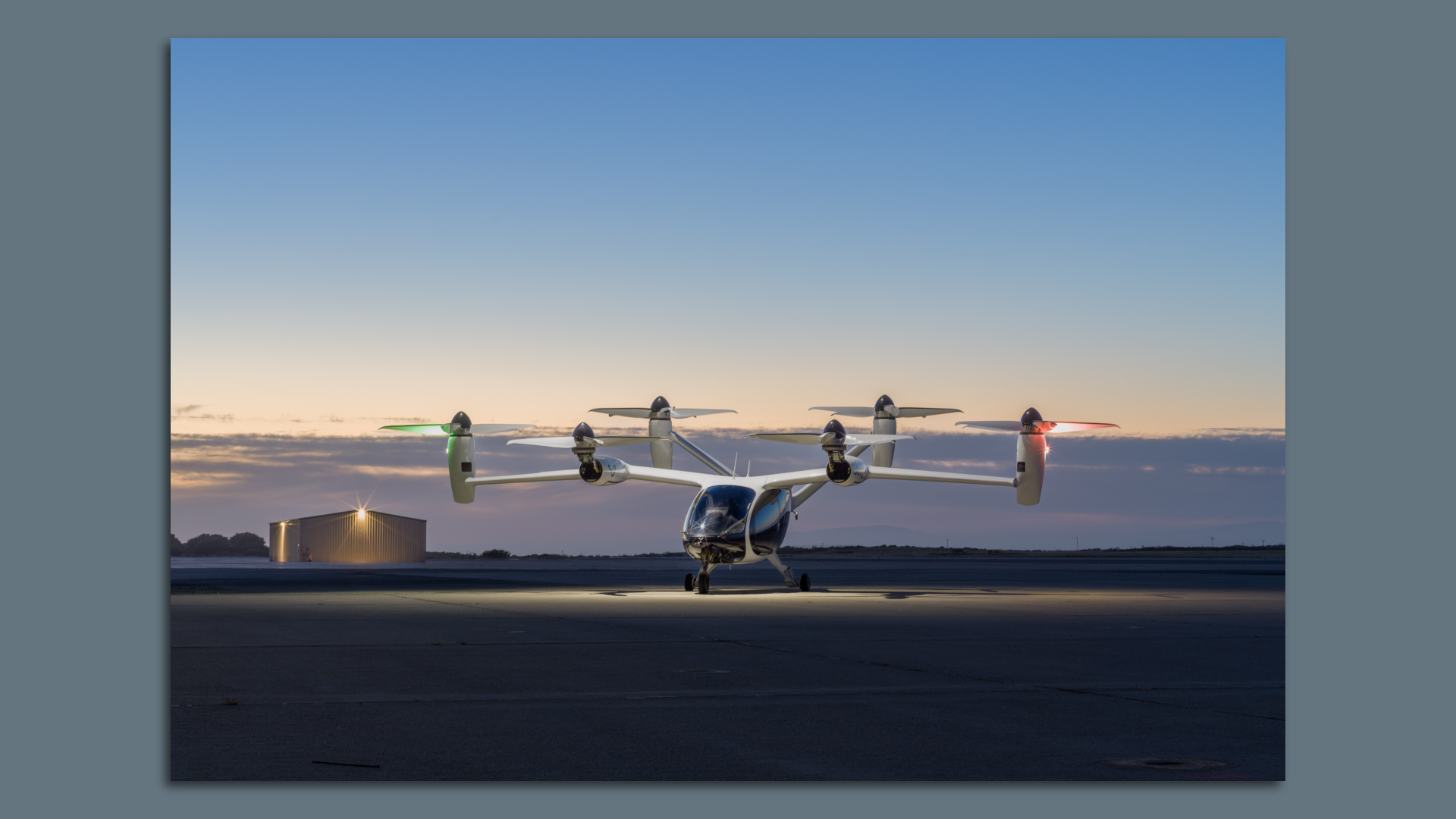 Image of Joby's multi-rotor electric vertical takeoff and landing aircraft on an airfield at dusk. 
