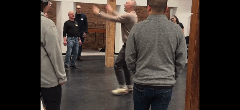 A man conducts inside a circle of people singing. 