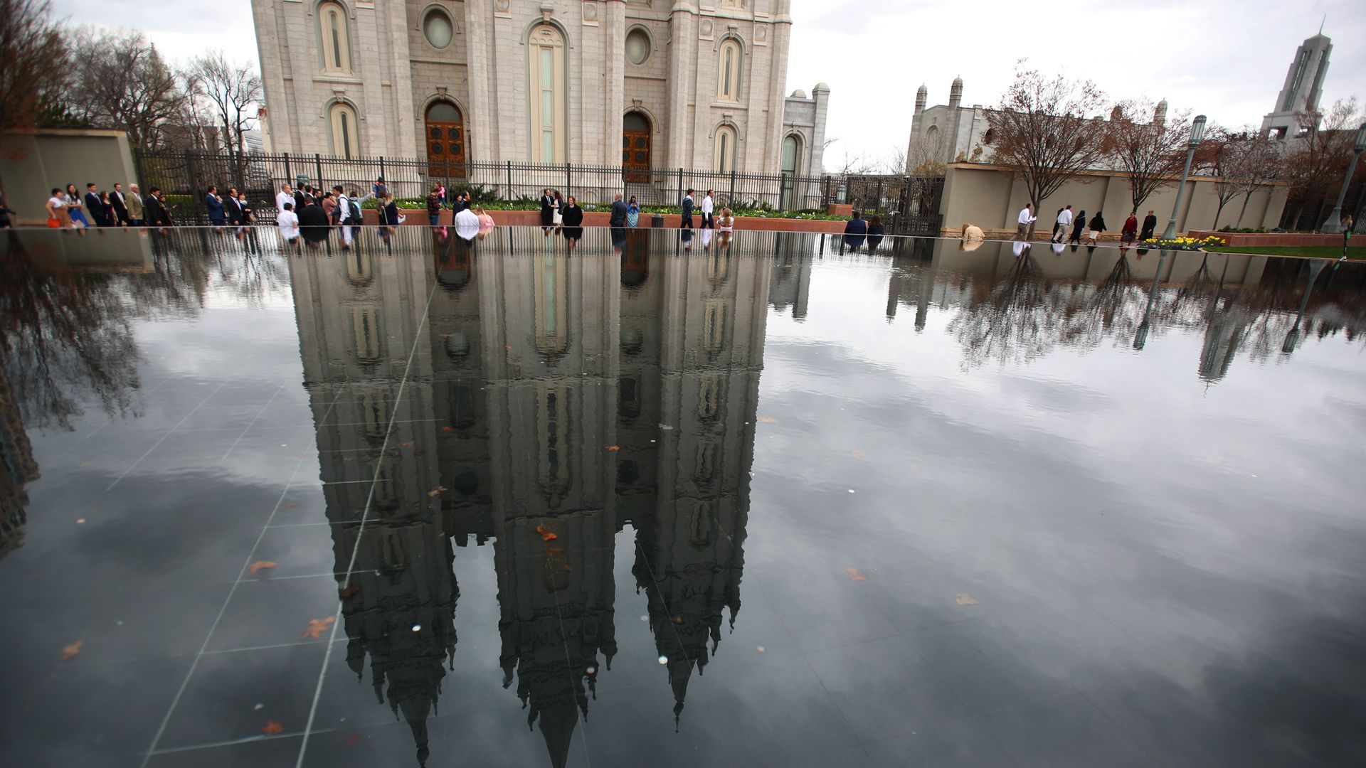  Conference goers walk past a reflection pool and the historic Salt Lake Temple of the Church of Jesus Christ of Latter-Day Saints 