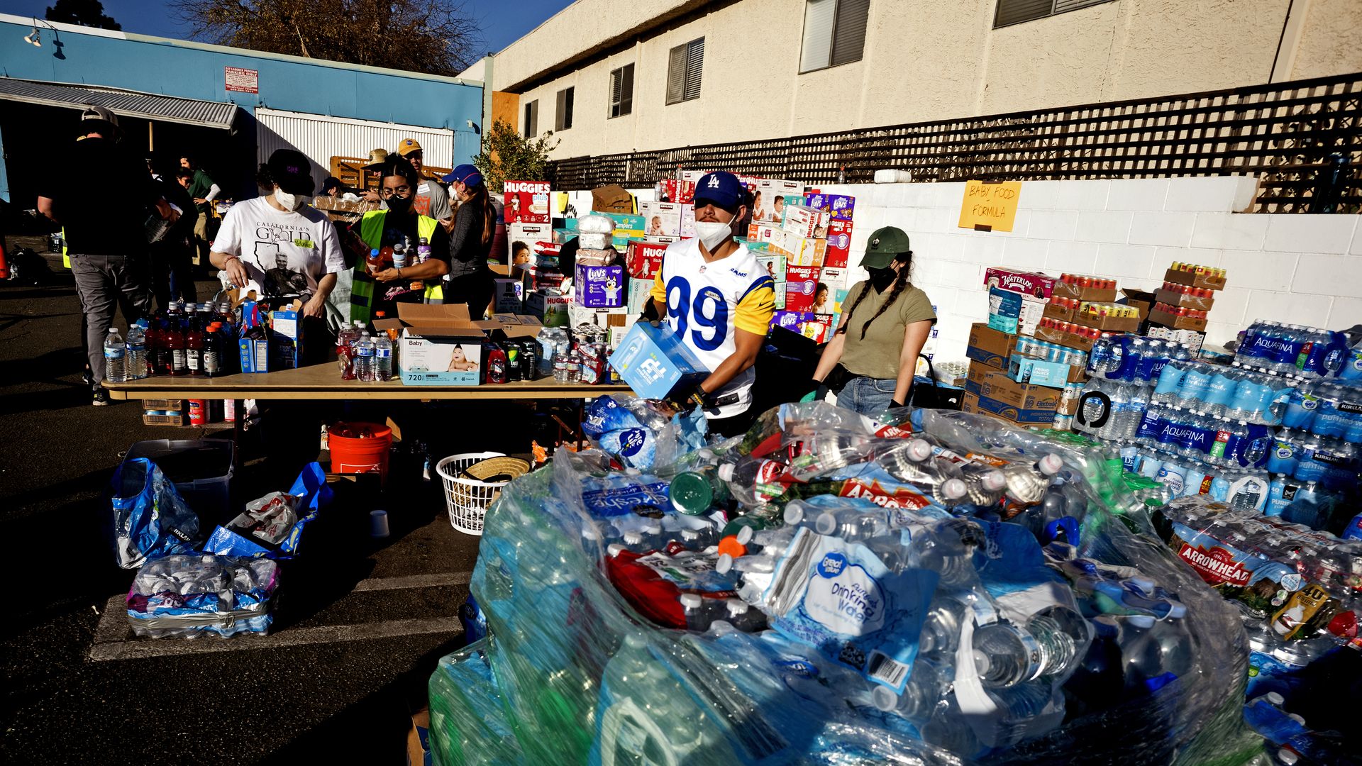 Volunteers help people load bags at a large donation site