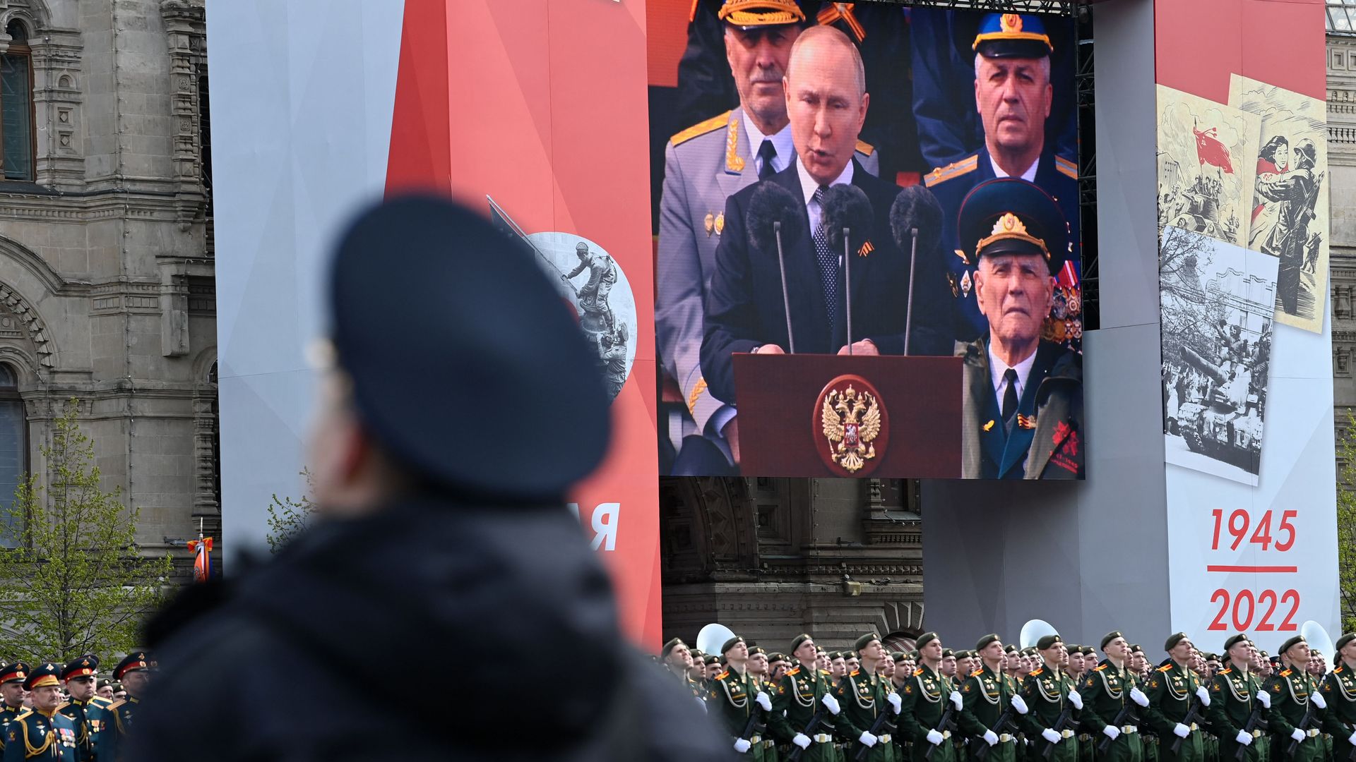 A screen shows Russian President Vladimir Putin giving a speech as servicemen line up on Red Square on May 9.