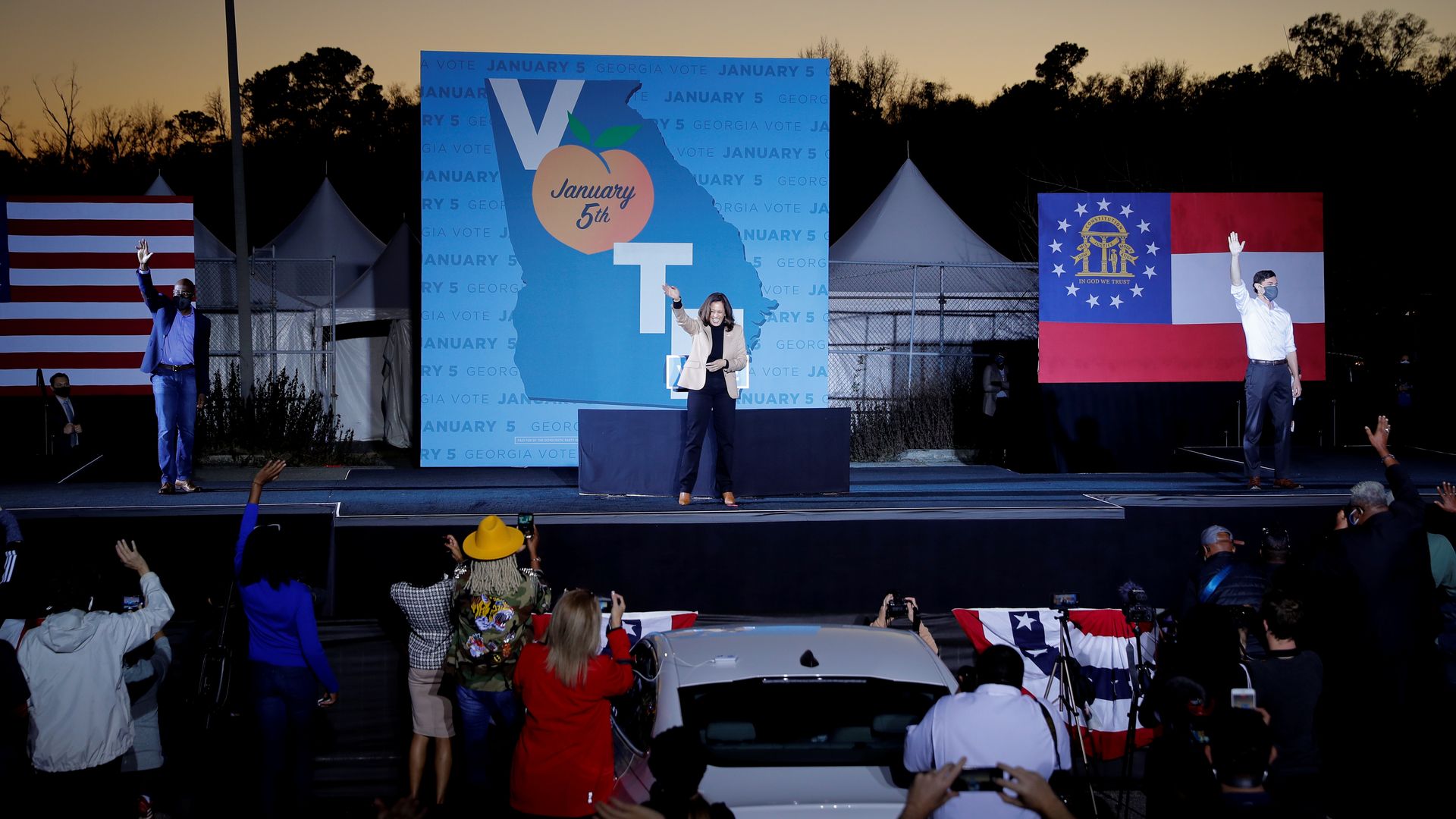 Kamala Harris is seen waving from a stage in Savannah, Ga., with Jon Ossoff and Raphael Warnock.