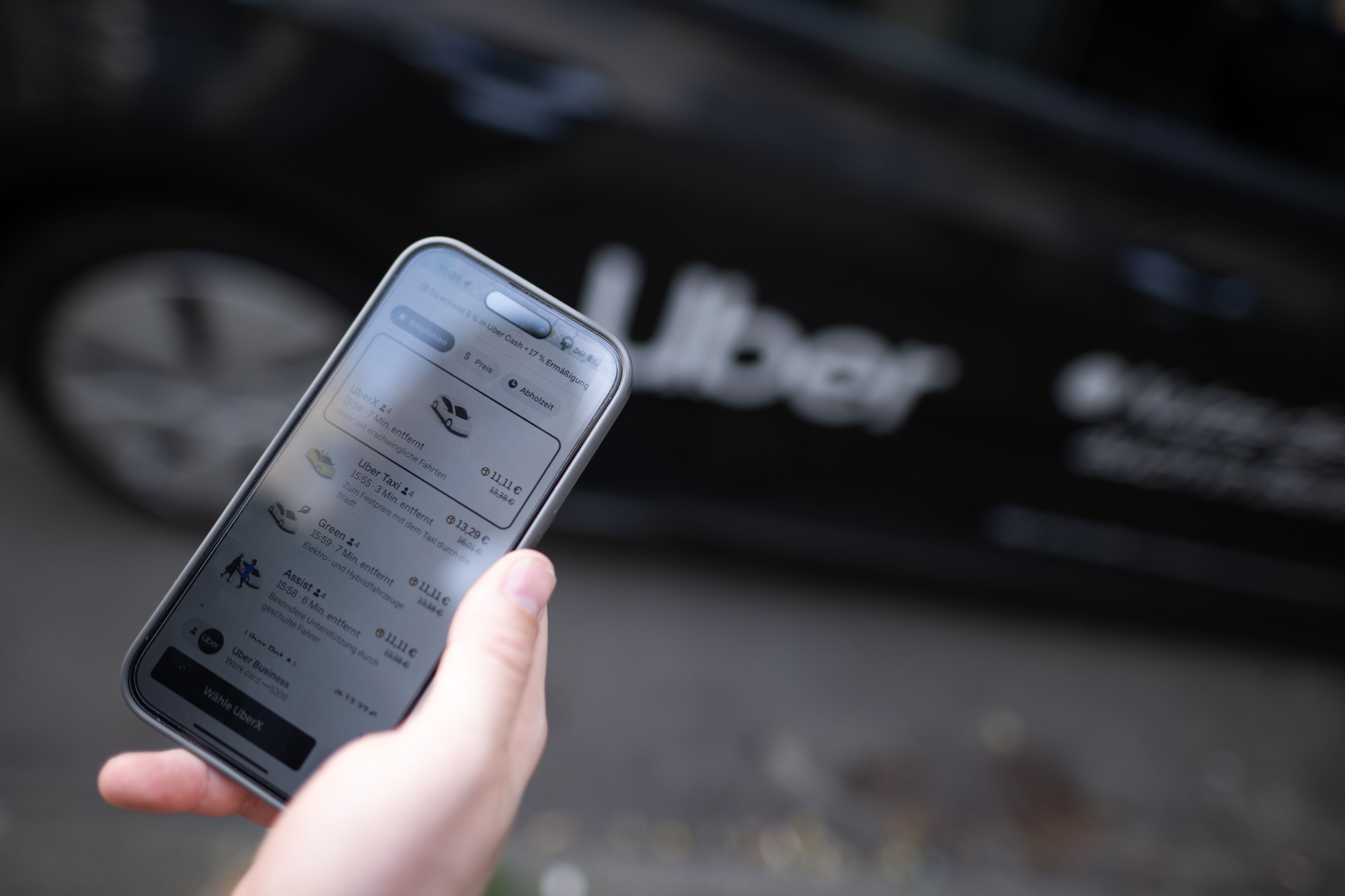 ILLUSTRATION - 08 August 2024, Berlin: A man stands in front of a rental car with a sign from the mobility service provider and ride broker Uber and holds his smartphone with the company's app in his hand. Photo: Sebastian Gollnow/dpa (Photo by Sebastian Gollnow/picture alliance via Getty Images)