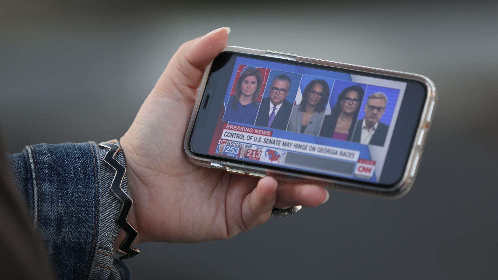 Photo of a hand holding a phone that has the CNN channel on