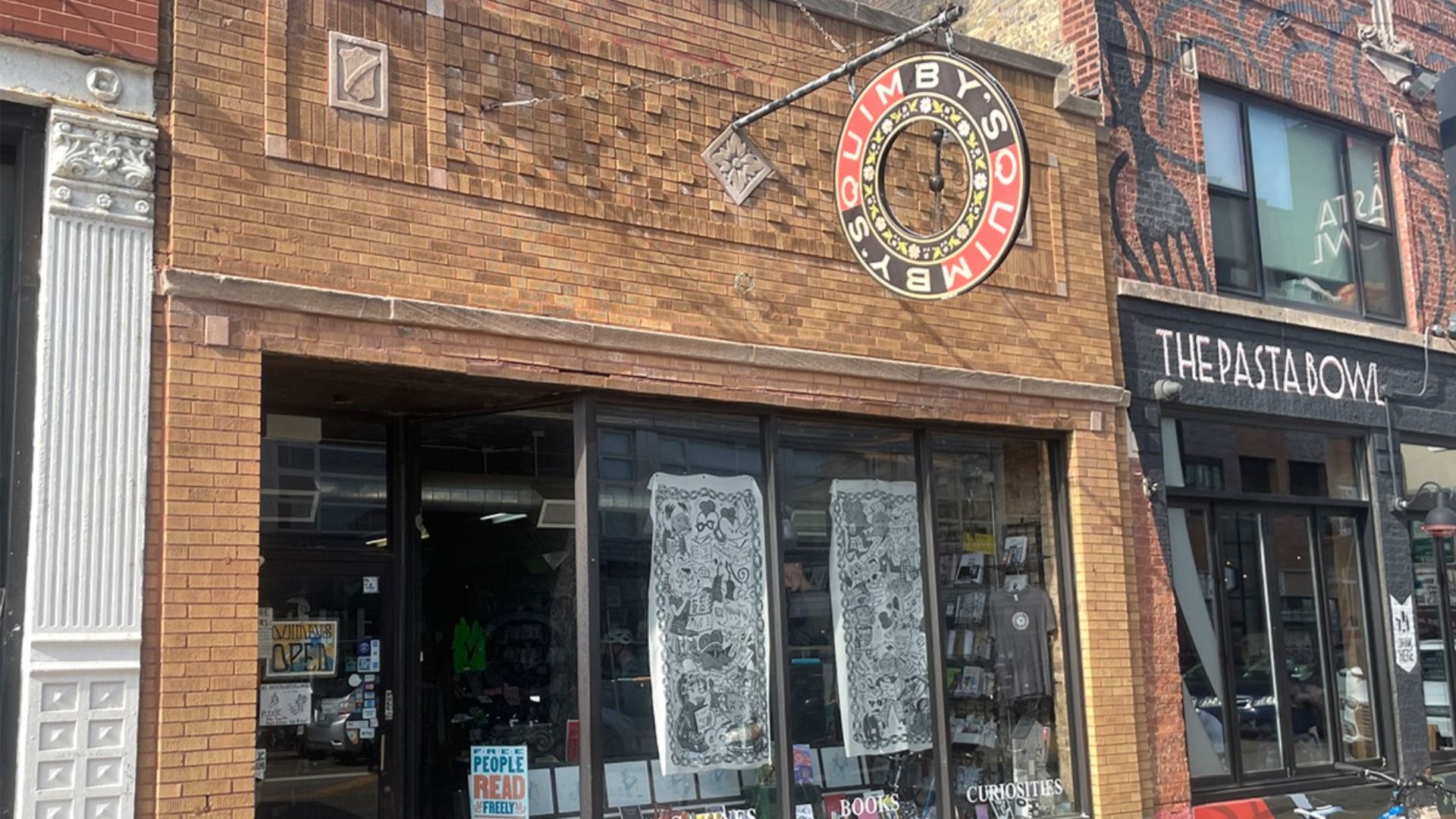 Brick storefront with a circular sign reading Quimby's in red and black.