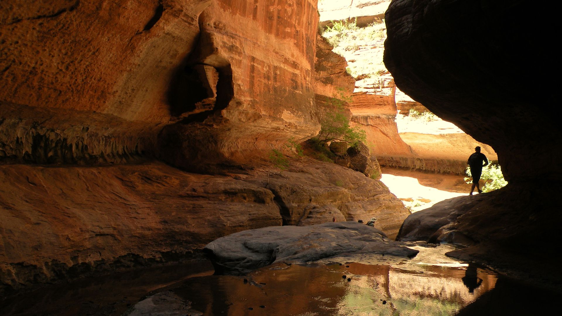 A hiker walks through a red rock canyon.