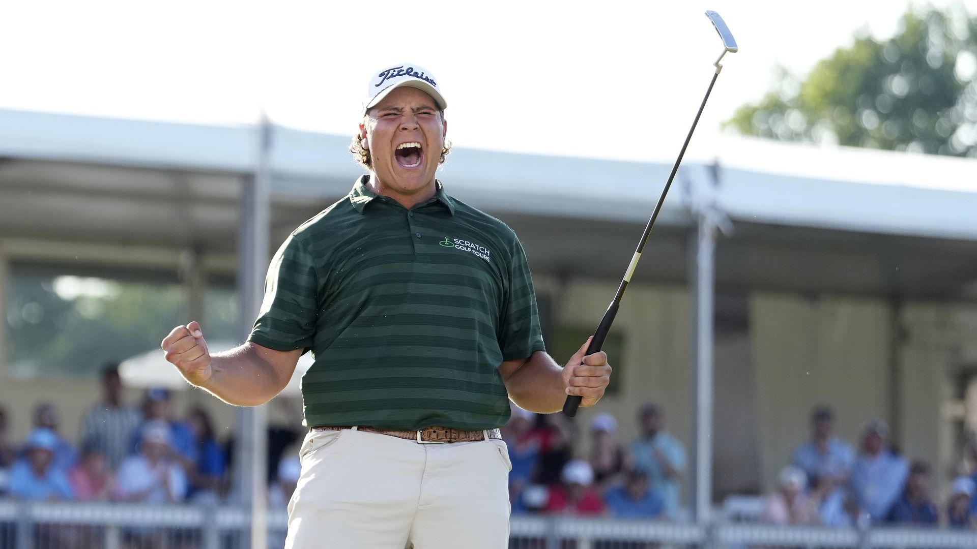 Potgieter yells with arms held out, while holding a golf club up