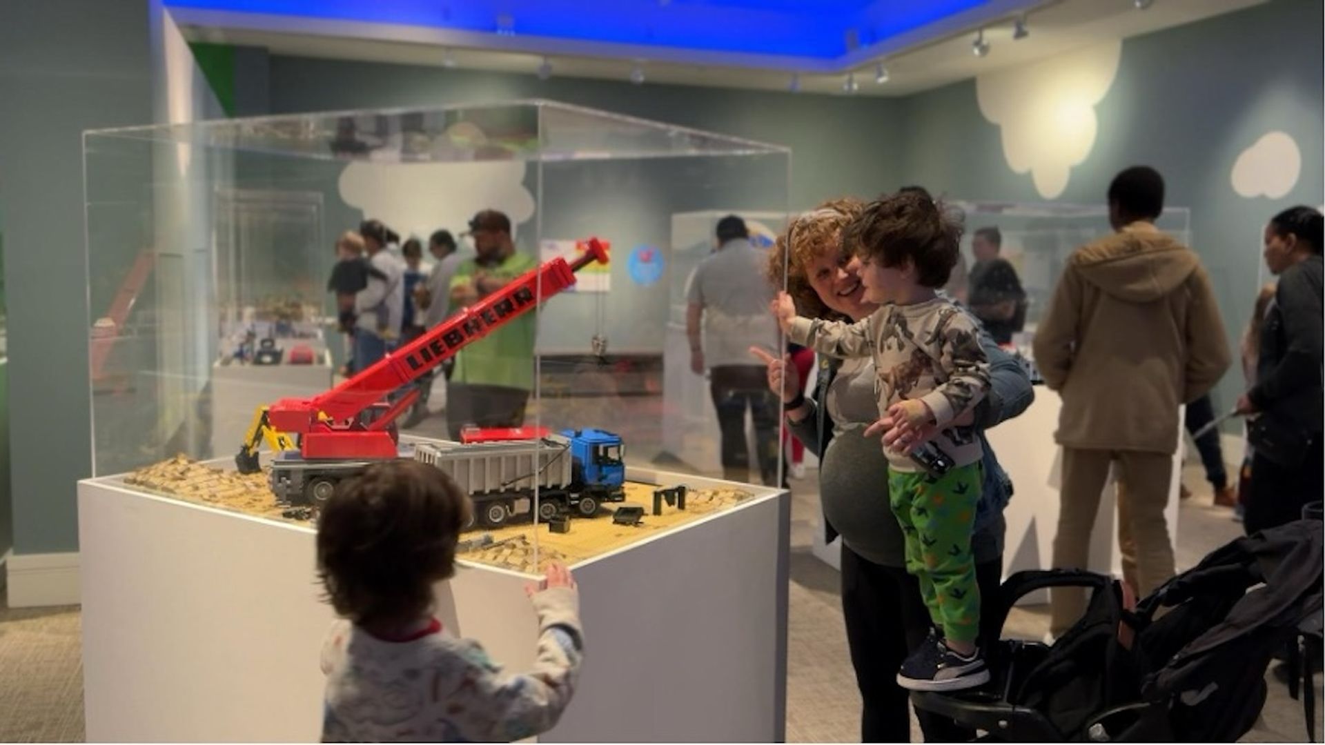 Two kids and a mom looking at a display of LEGO® bricks.