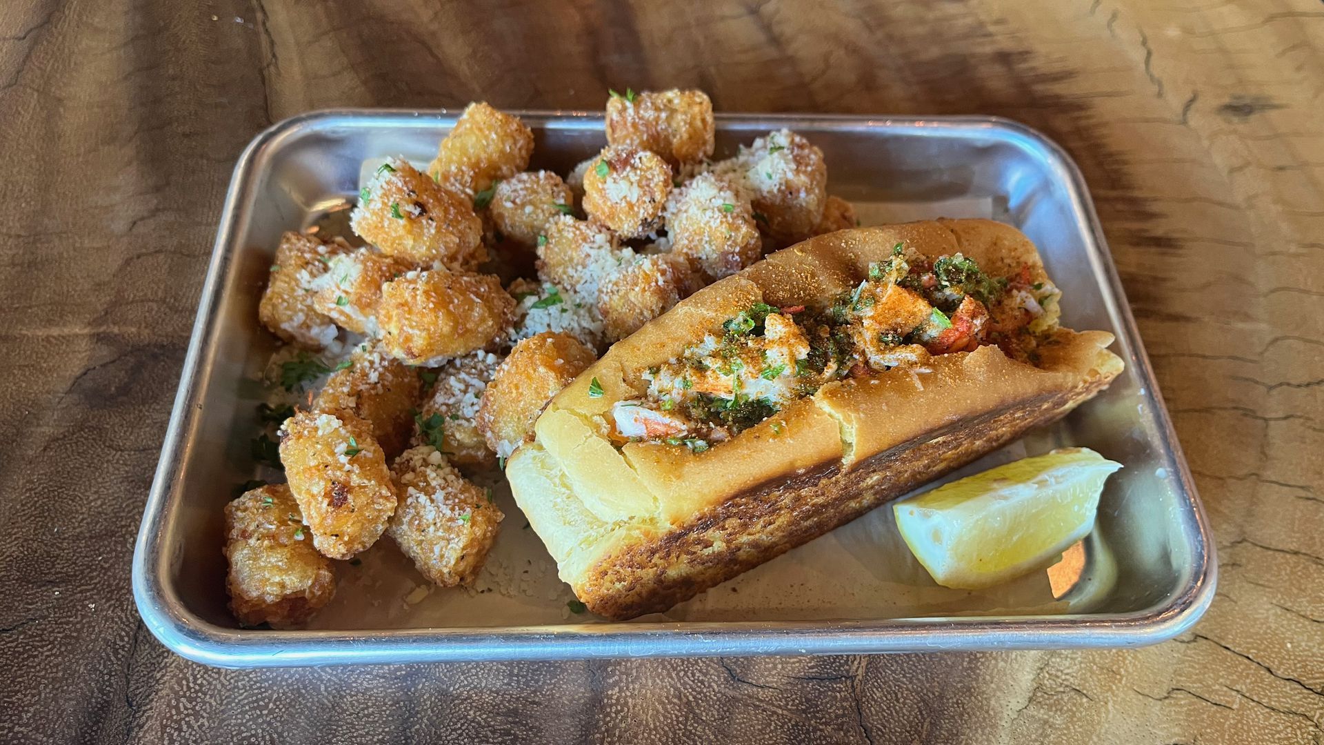 A lobster roll with tater tots.