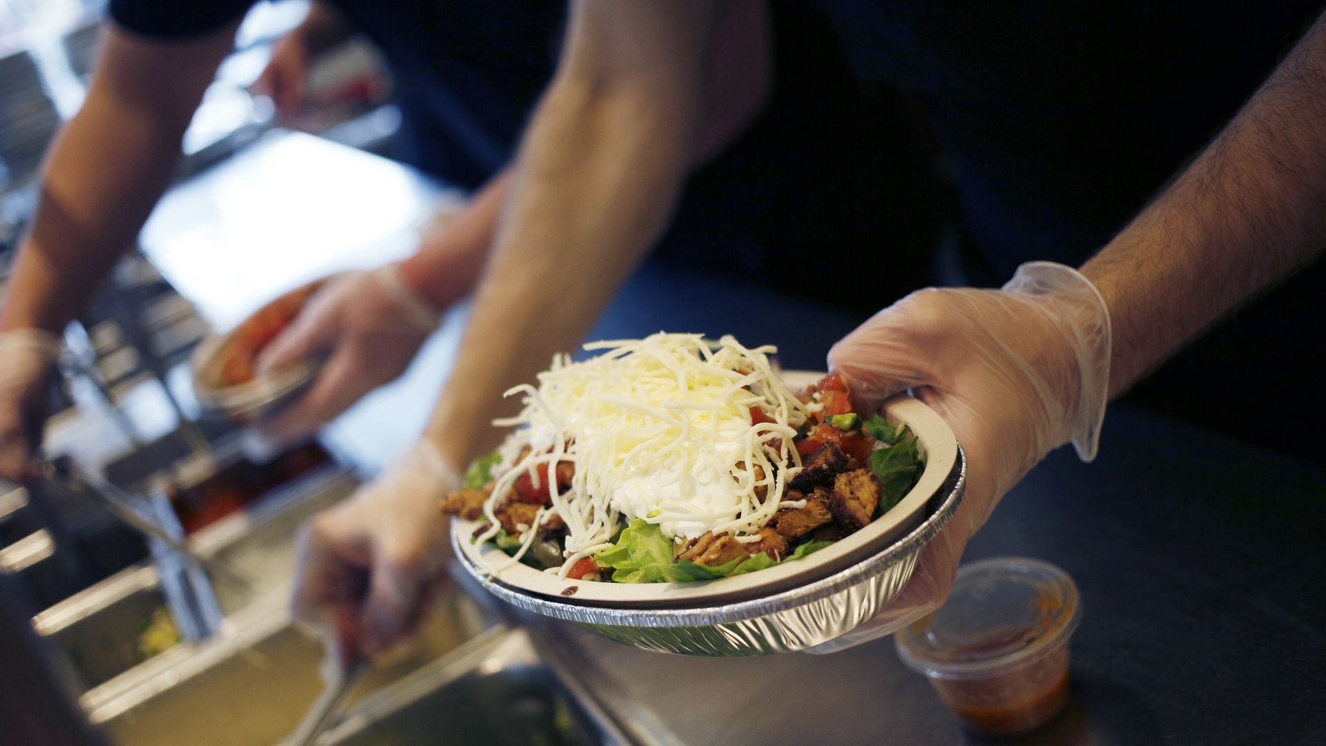 Chipotle worker fills a burrito bowl