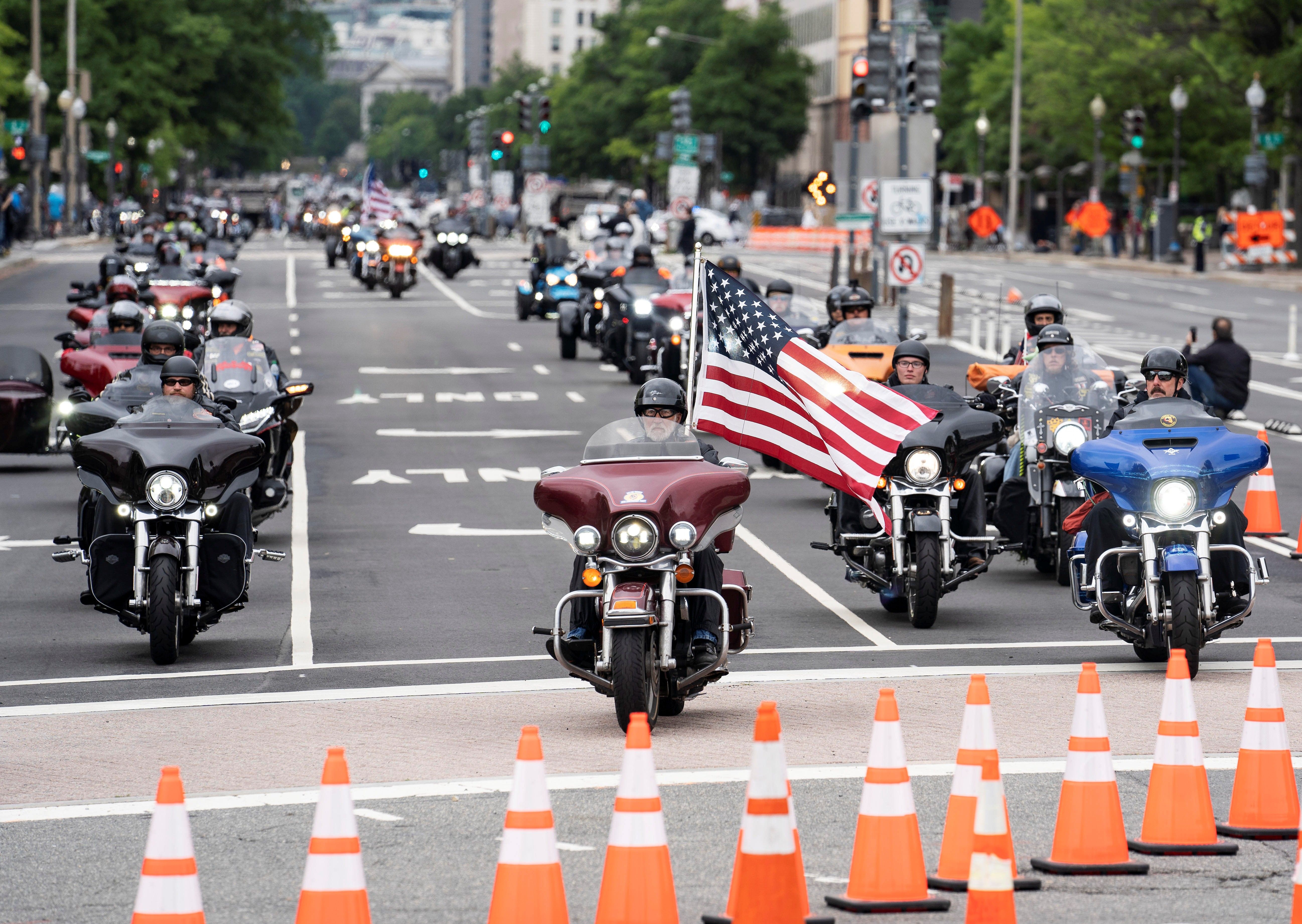 A motorcycle carrying an American flag drives towards orange cones