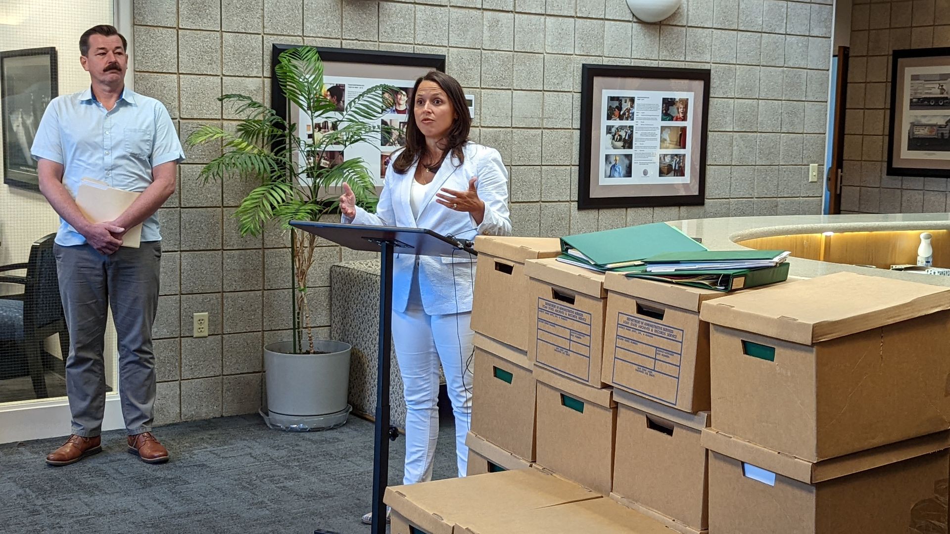 Tiffany Clason, director of Utah's alcohol enforcement agency, stands next to boxes of soon-to-be-discarded paperwork at a news conference announcing the department's move to digital permitting. Cade Campbell, a resort manager in Springdale, looks on. Photo: Erin Alberty