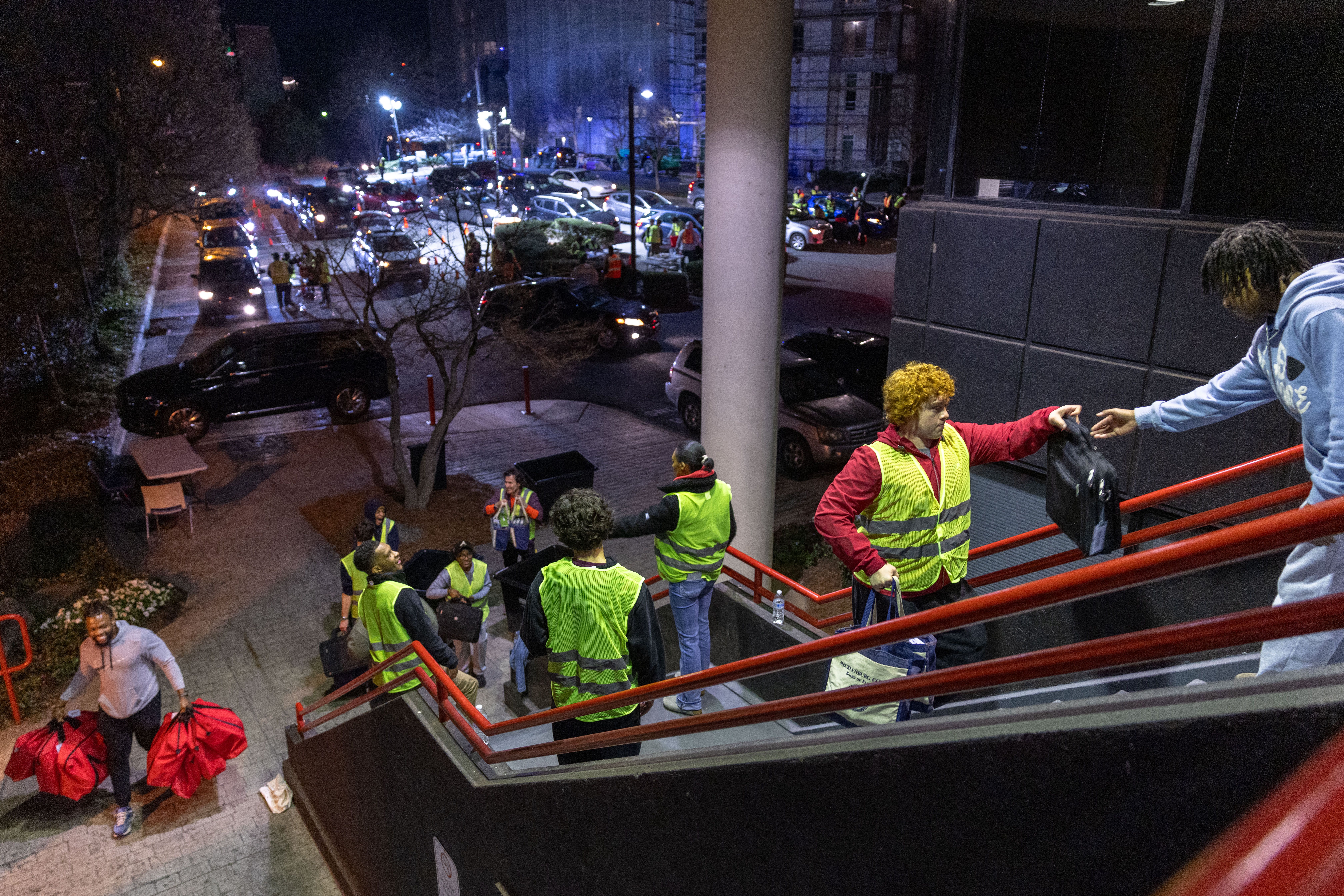 Poll workers wearing fluorescent vests drop off bags of ballots and other materials at the Mecklenburg County Board of Elections offices after dark on primary election day.
