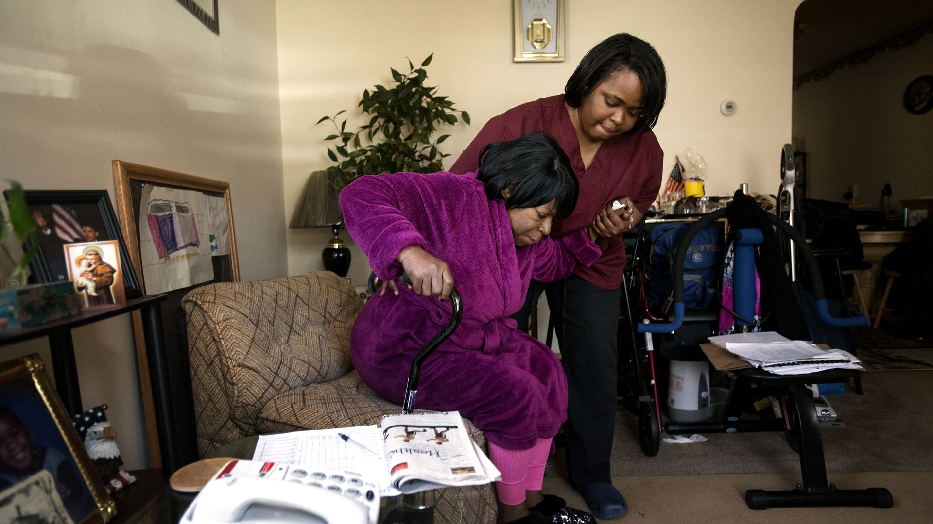 A home health aide helps a patient at her house.