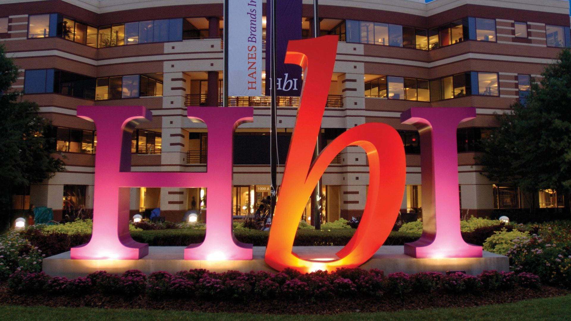 Giant letters h, b and i are illuminated in front of a corporate building