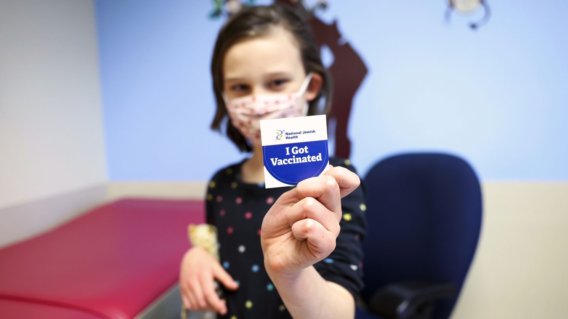 A photo of a young girl holding a sticker that reads, "I got vaccinated."