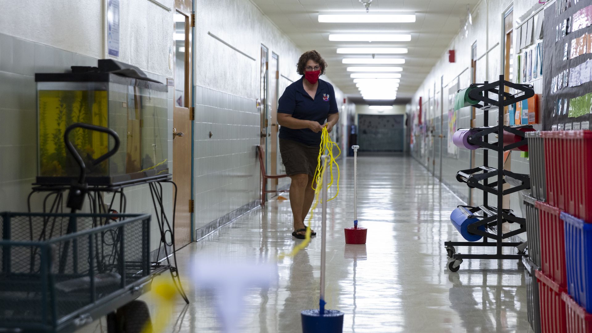 A teacher prepares a hallway barrier to help students maintain social distancing 