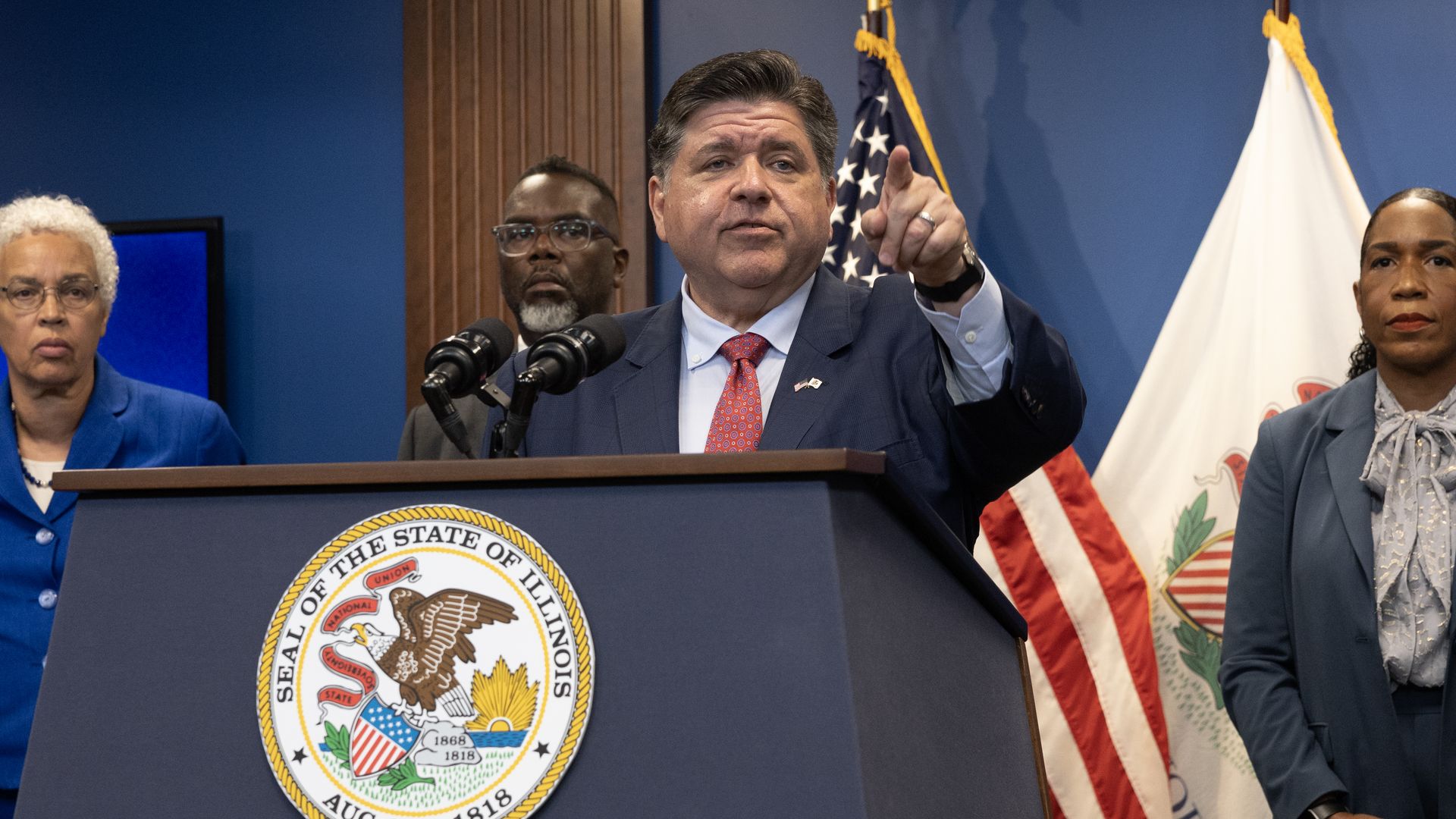 Photo of a man behind a podium pointing at the audience. 