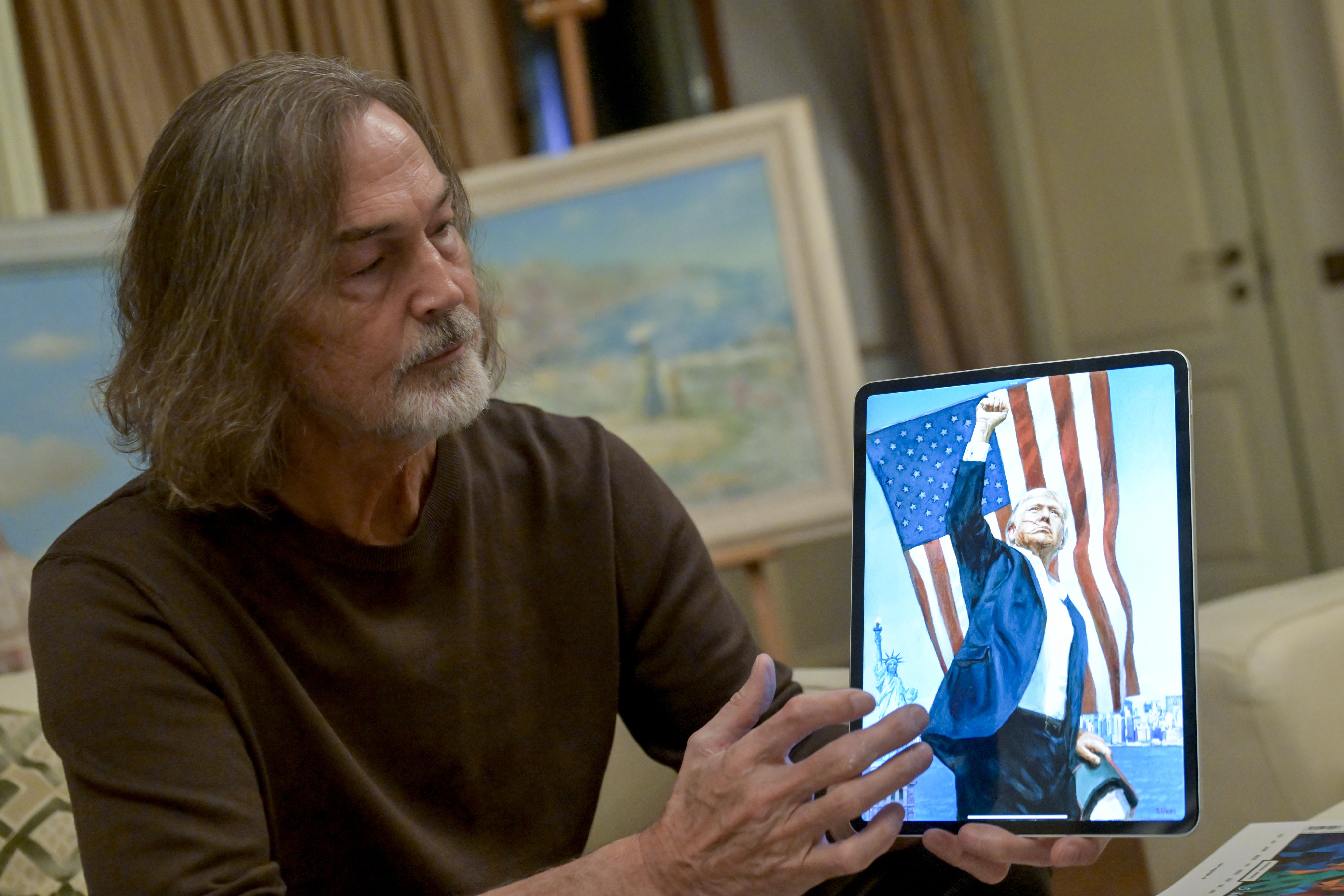 薩夫羅諾夫身穿綠色襯衫，手持平板電腦，螢幕上顯示川普舉起拳頭的畫像。